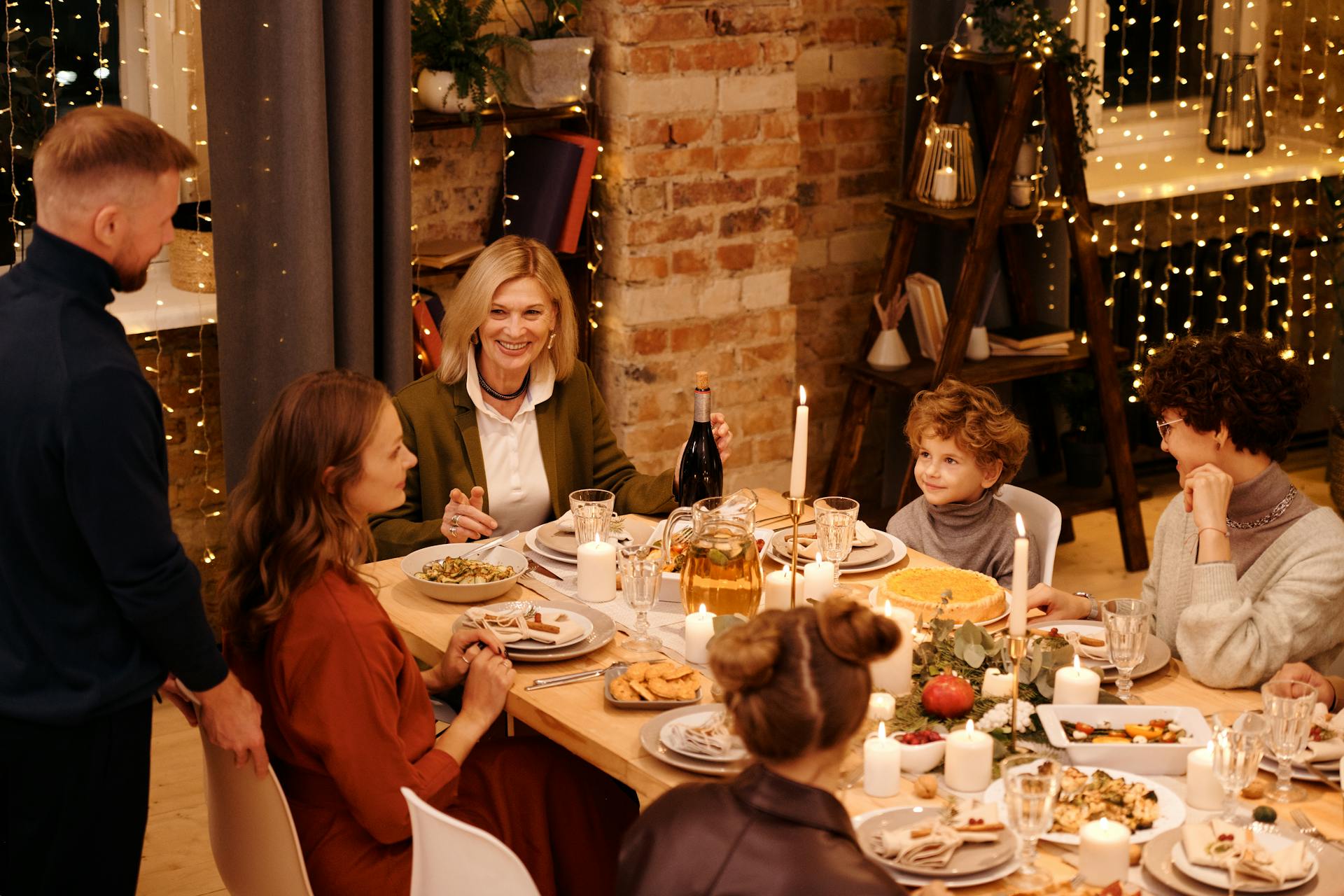 Eine Familie sitzt bei einem Festtagsschmaus um einen Tisch mit Kerzenlicht | Quelle: Pexels
