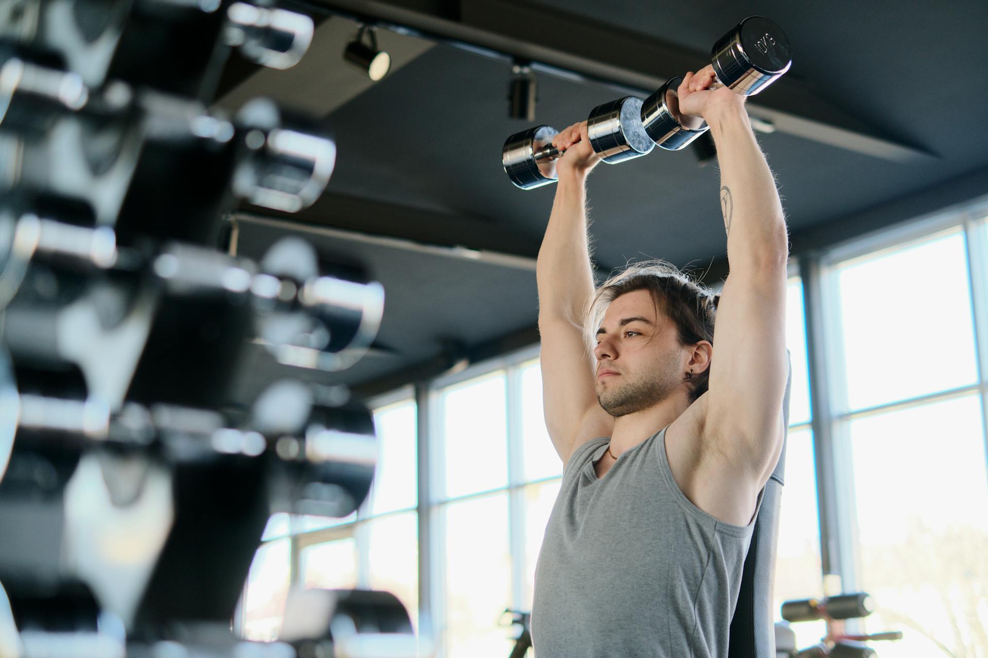 Ein Mann trainiert mit Hanteln in einem Fitnessstudio | Quelle: Pexels