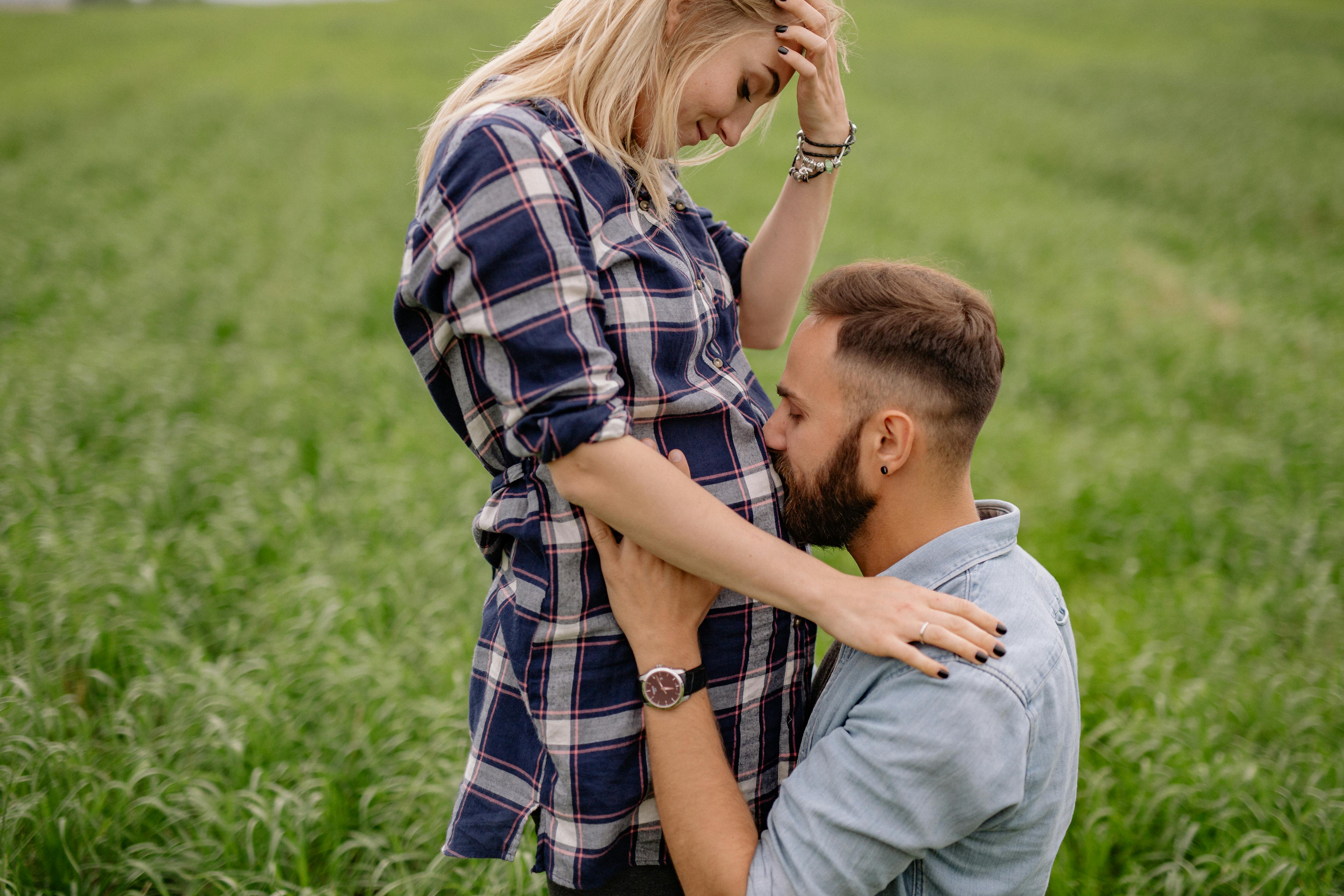 Ein Mann küsst den schwangeren Bauch einer Frau | Quelle: Pexels