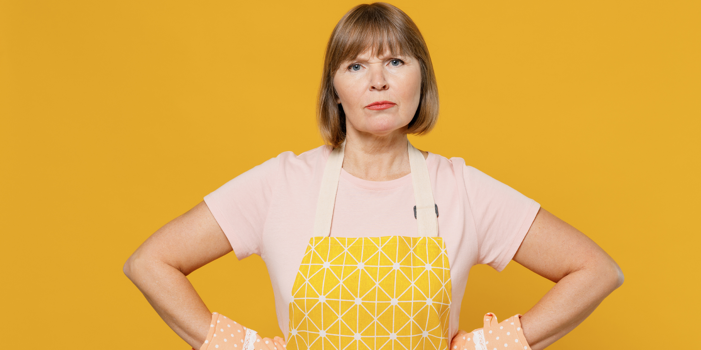 Eine aufgebrachte Frau mit Schürze und Ofenhandschuhen | Quelle: Shutterstock