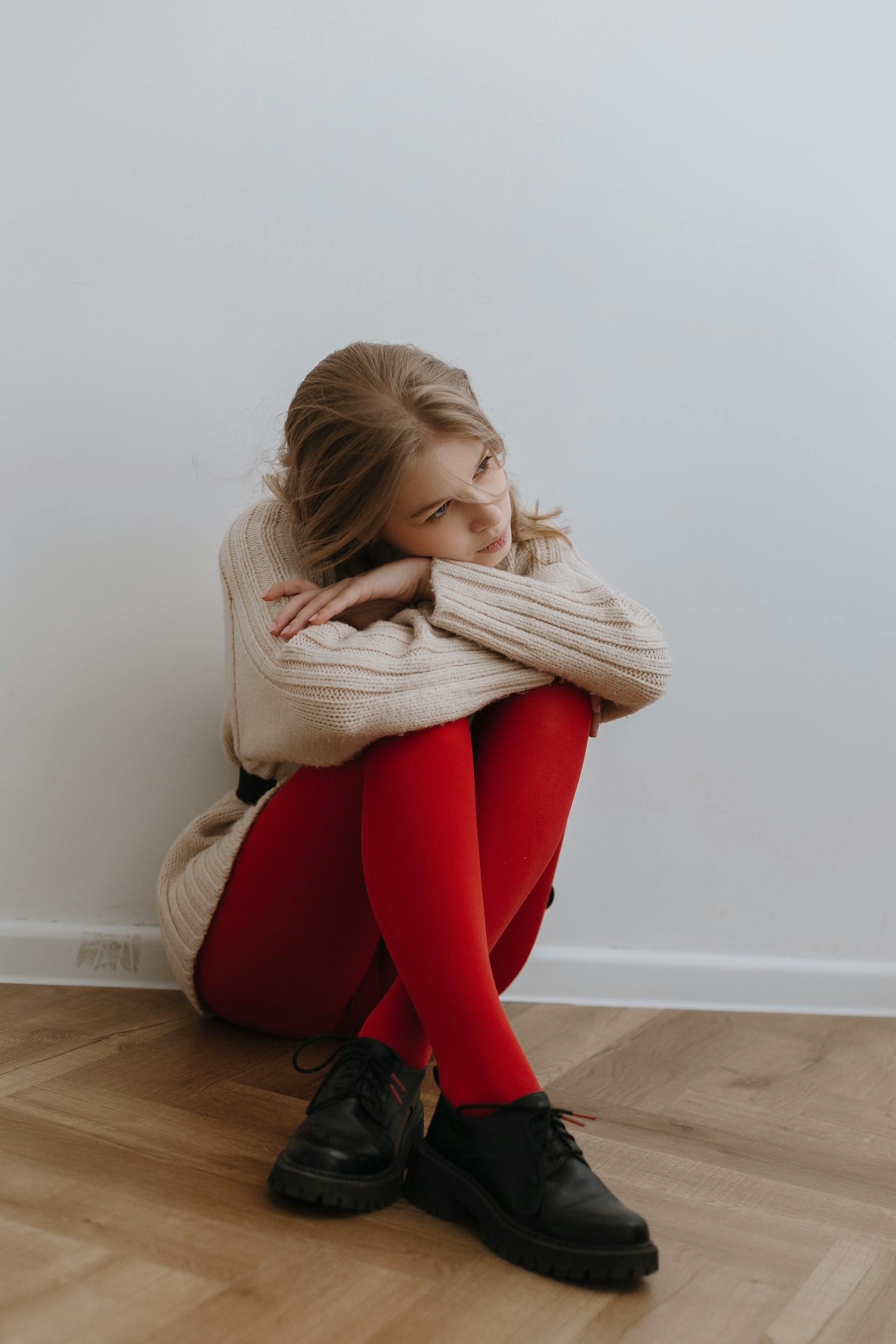 Eine müde Frau sitzt auf dem Boden an der Wand | Quelle: Pexels