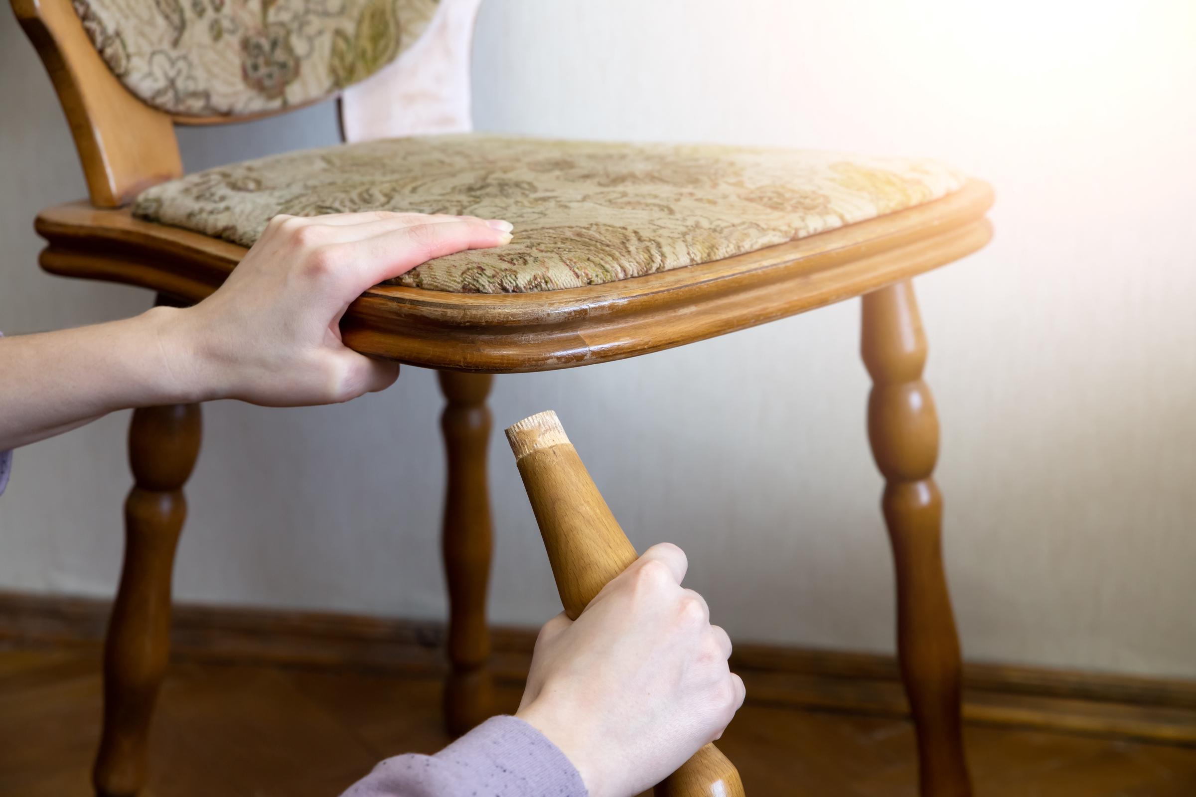 Eine Nahaufnahme einer Frau, die das Bein eines zerbrochenen Stuhls hält | Quelle: Shutterstock