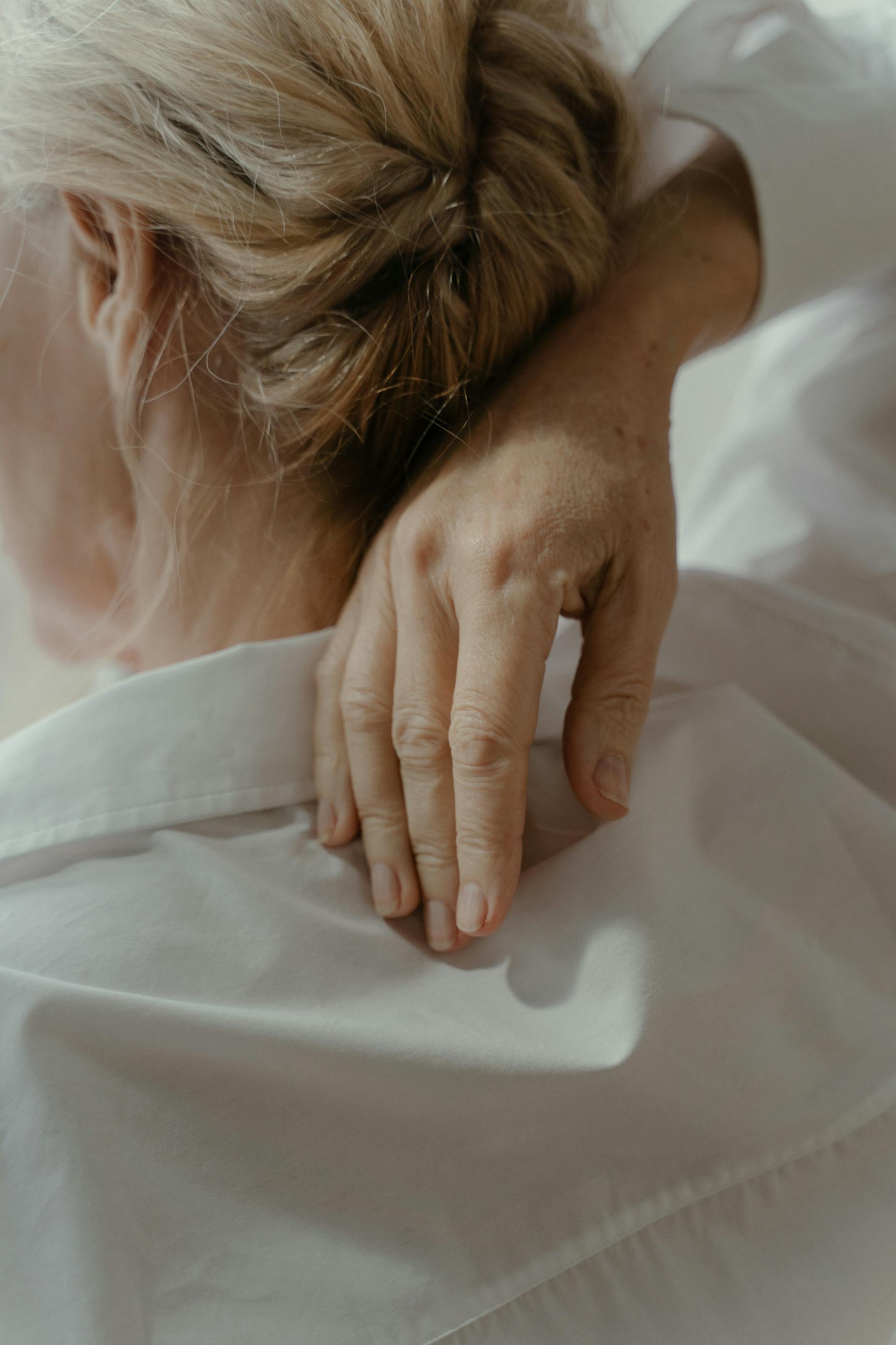 Eine ältere Frau, die mit einer Hand ihren Rücken berührt | Quelle: Pexels
