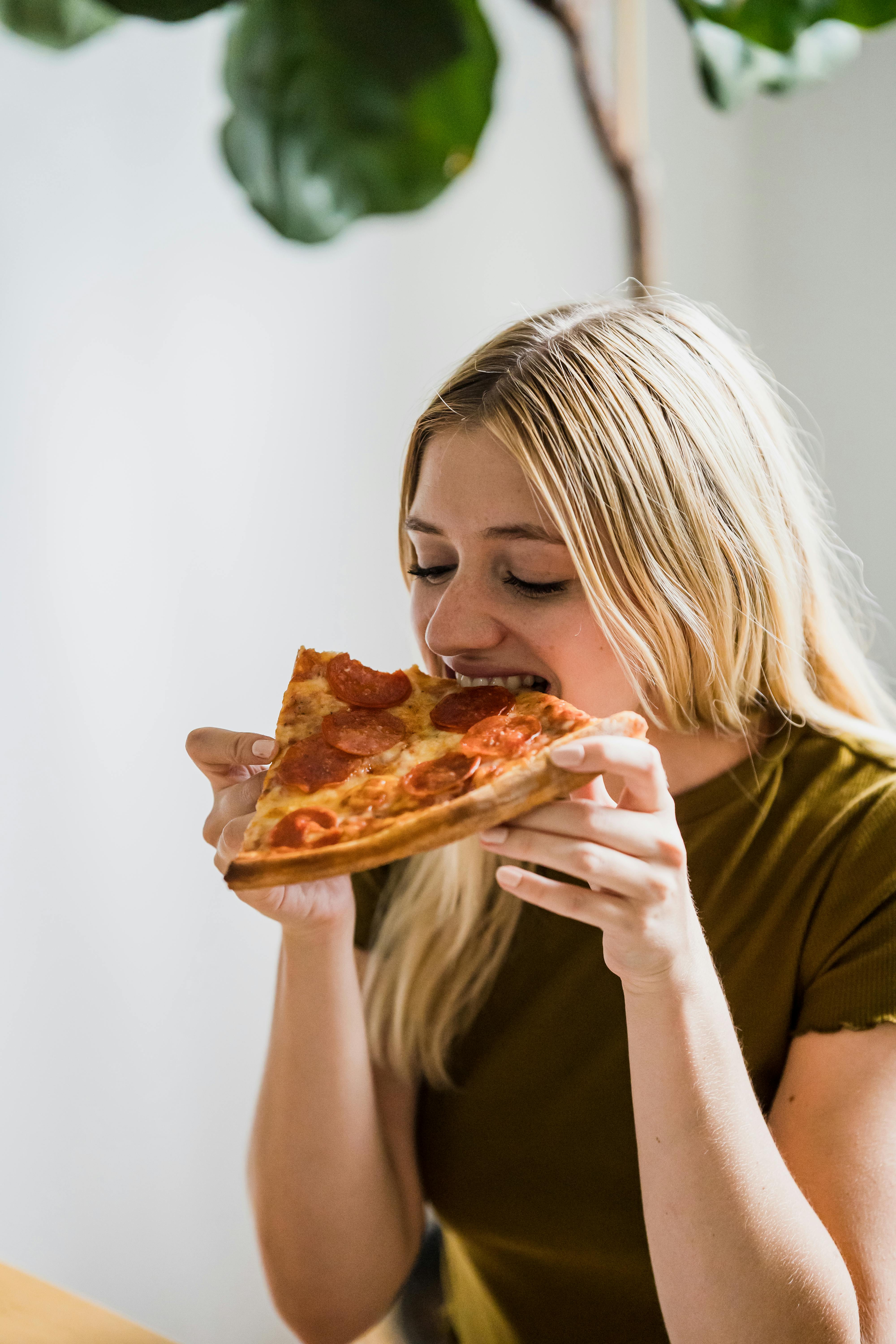 Eine glückliche Frau beim Pizzaessen | Quelle: Pexels