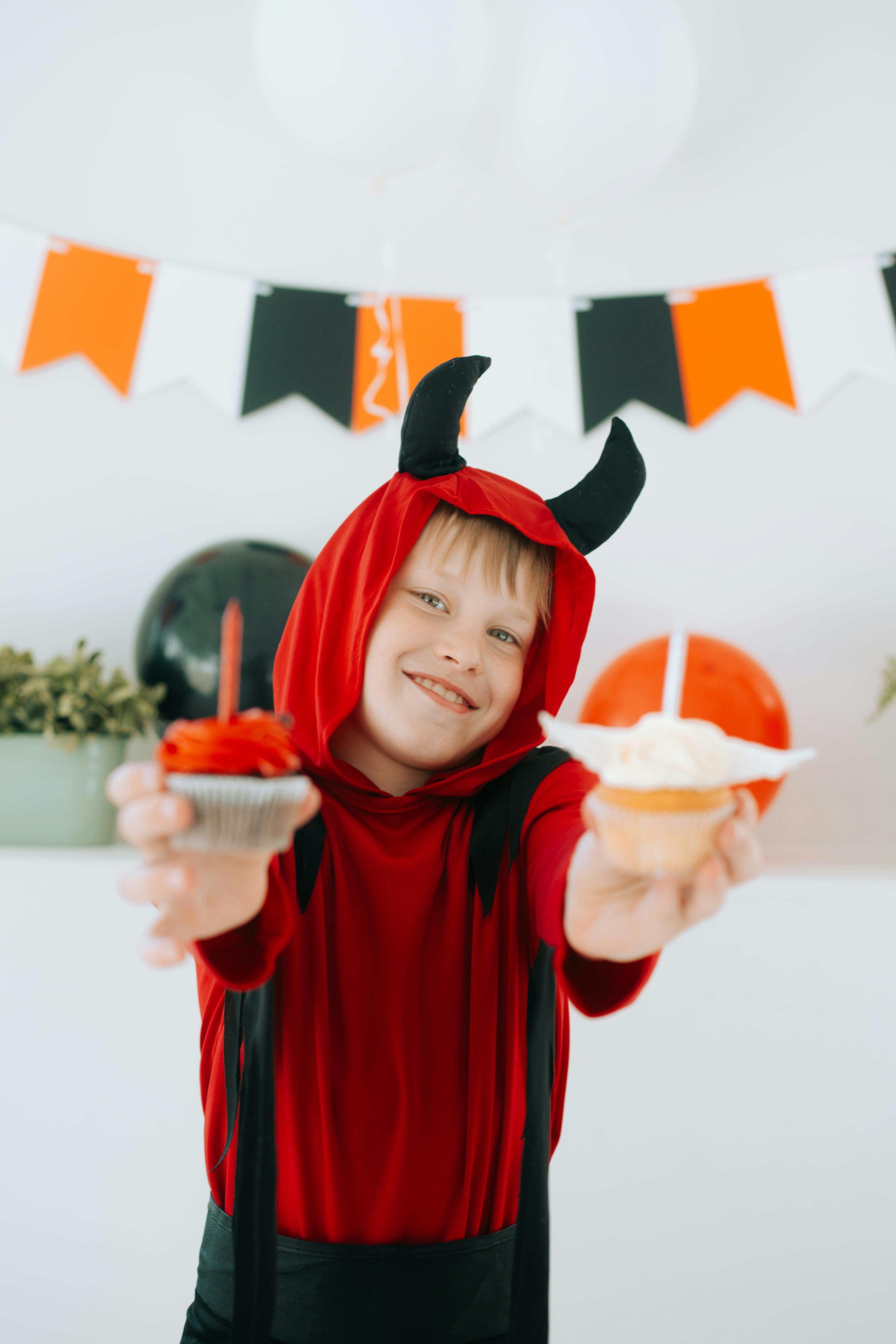 Ein kleiner Junge, der für Halloween gekleidet ist und Leckereien in der Hand hält | Quelle: Pexels