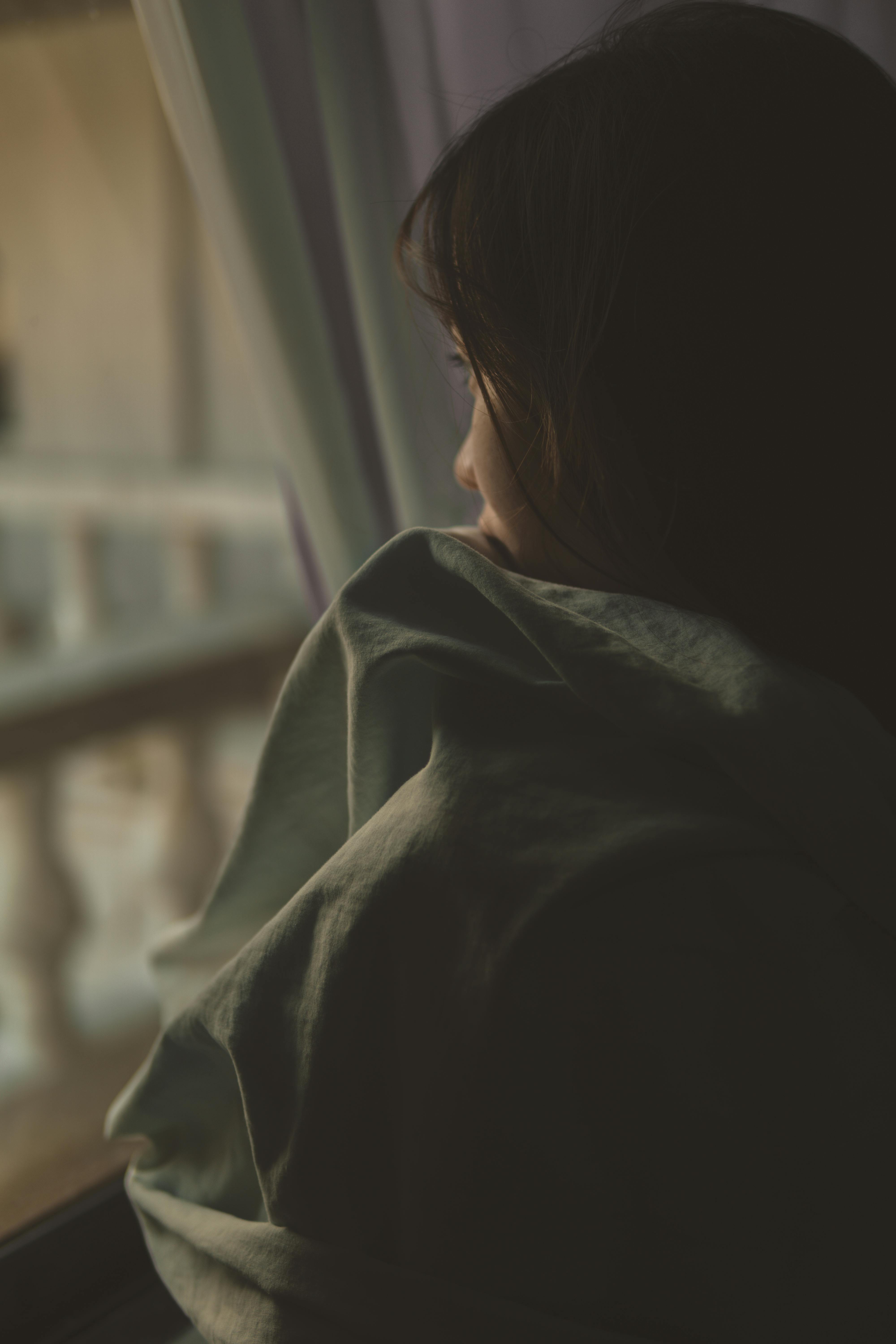 Eine traurige Frau, die aus einem Fenster schaut | Quelle: Pexels