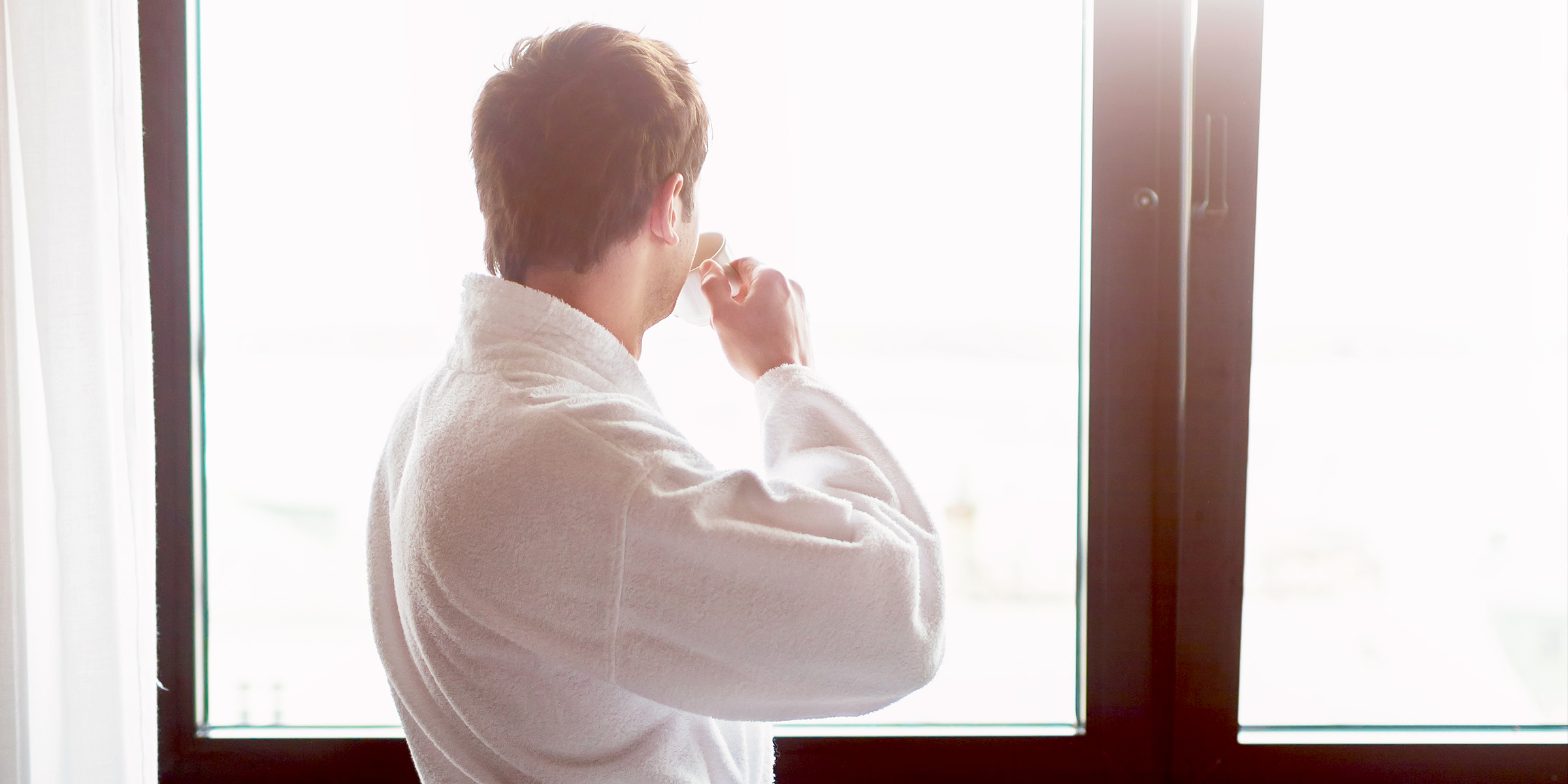 Ein Mann trinkt seinen Morgenkaffee am Fenster | Quelle: Shutterstock
