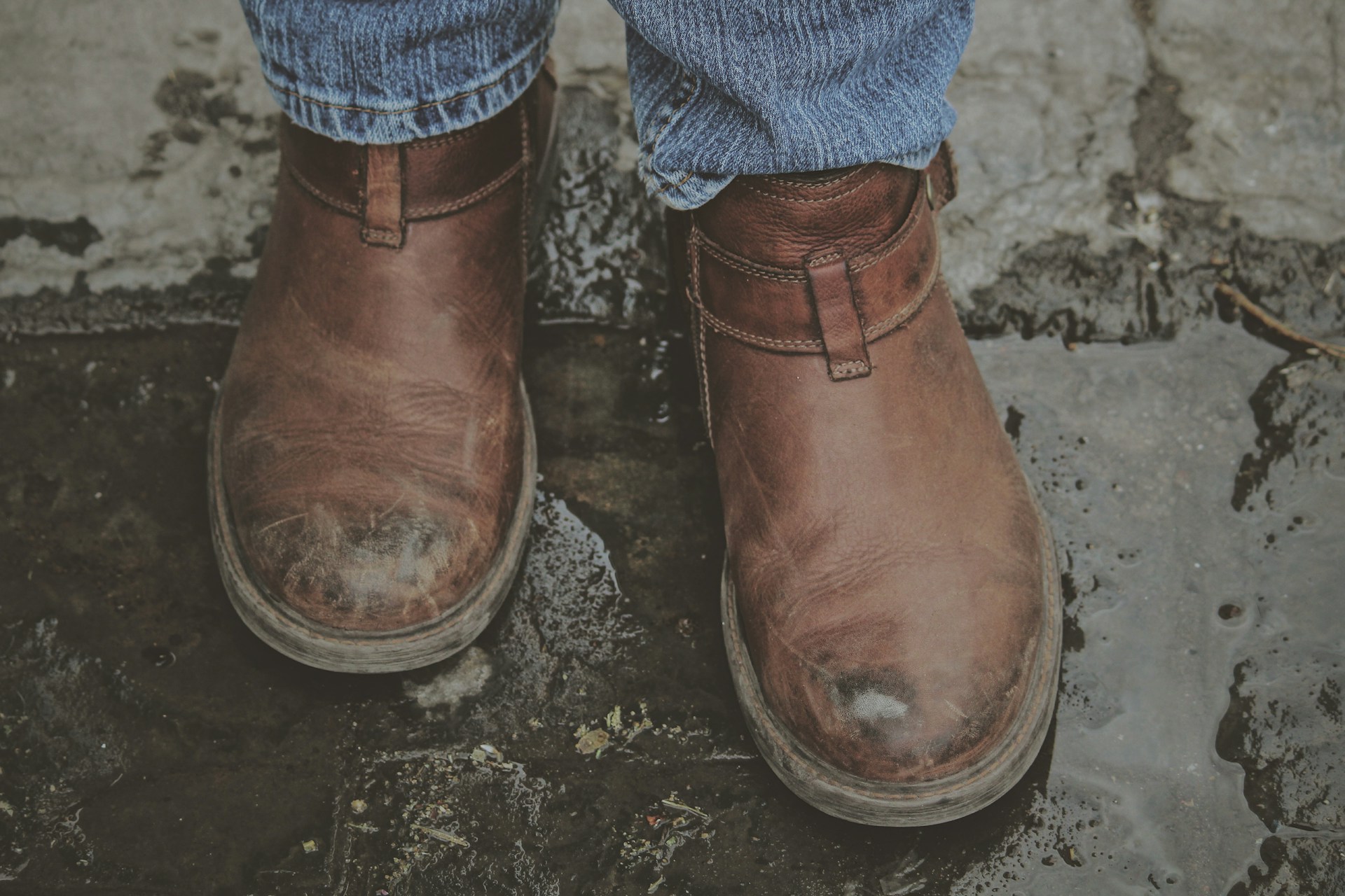 Jemand, der Stiefel trägt und durch eine Pfütze läuft | Quelle: Unsplash