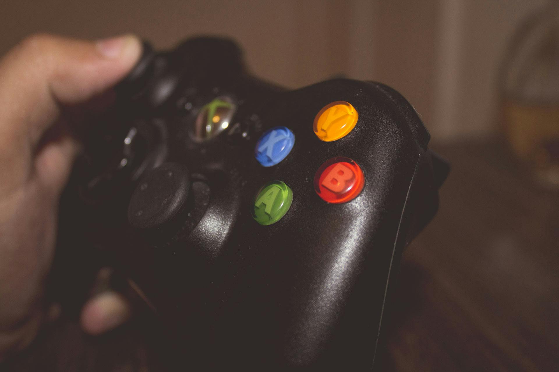 Eine Person hält eine Spielkonsolen-Fernbedienung hoch | Quelle: Pexels