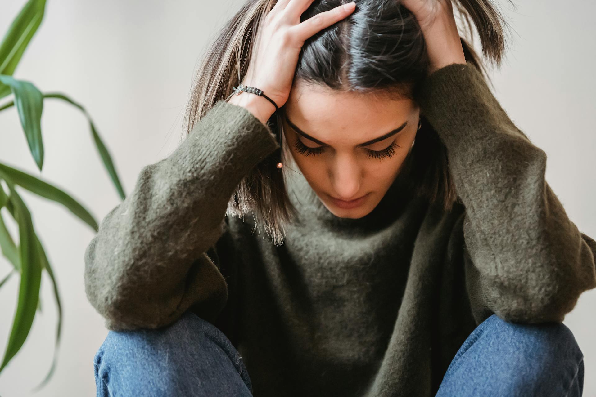 Eine Frau sitzt mit dem Kopf in den Händen | Quelle: Pexels