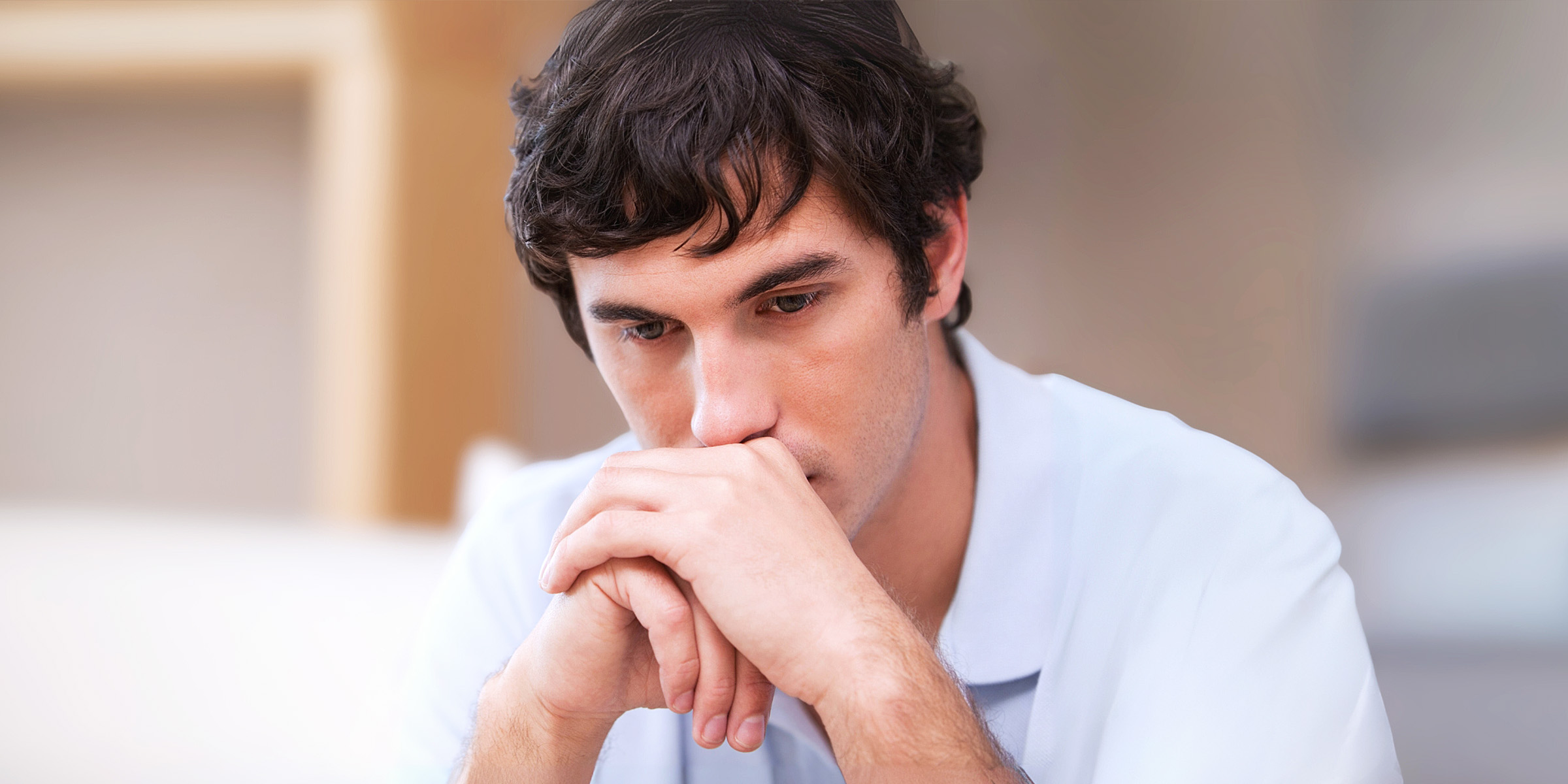 Ein nachdenklicher Mann sitzt in einem Wohnzimmer | Quelle: Shutterstock