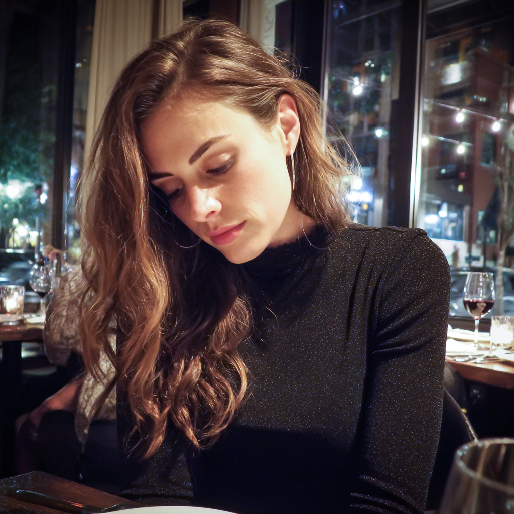 Eine Frau, die in einem Restaurant auf ihren Schoß hinunterschaut | Quelle: Midjourney
