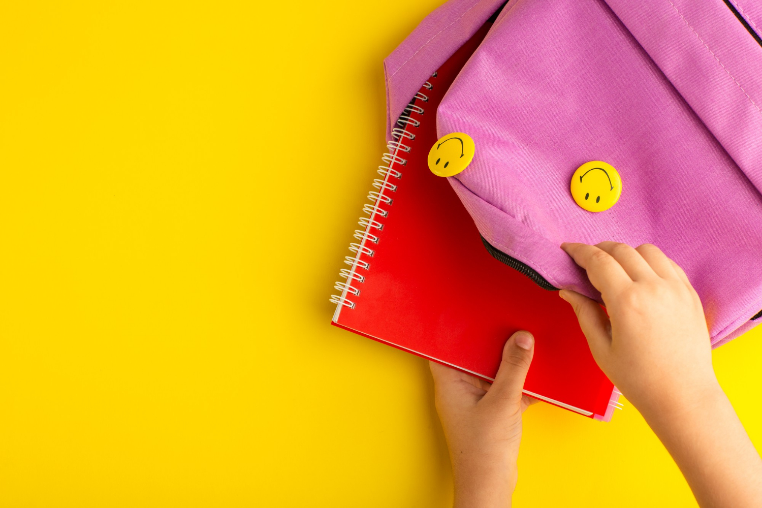 Nahaufnahme eines Kindes, das ein Notizbuch in eine rosa Tasche steckt | Quelle: Freepik