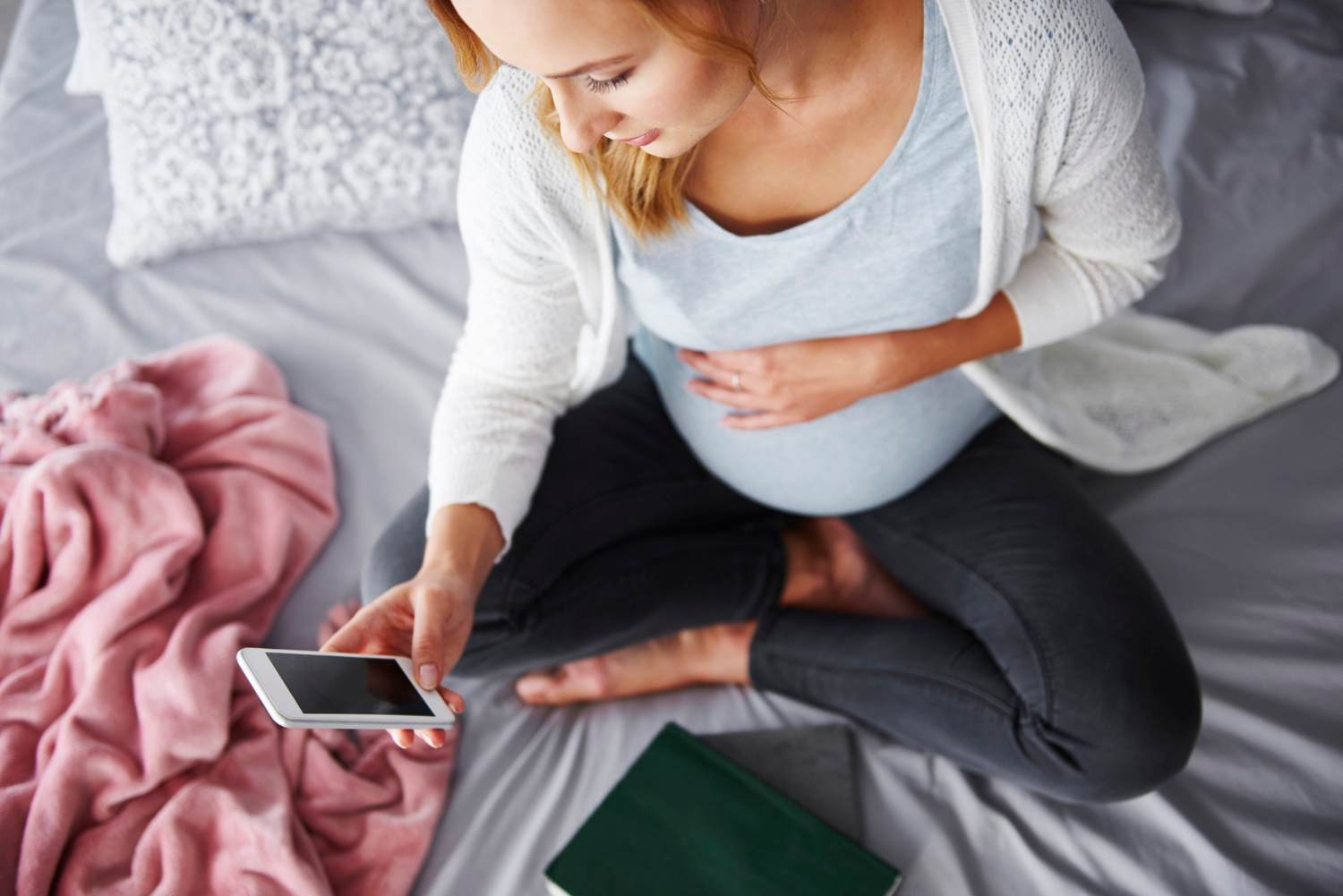 Eine schwangere Frau schaut auf ihr Telefon | Quelle: Freepik