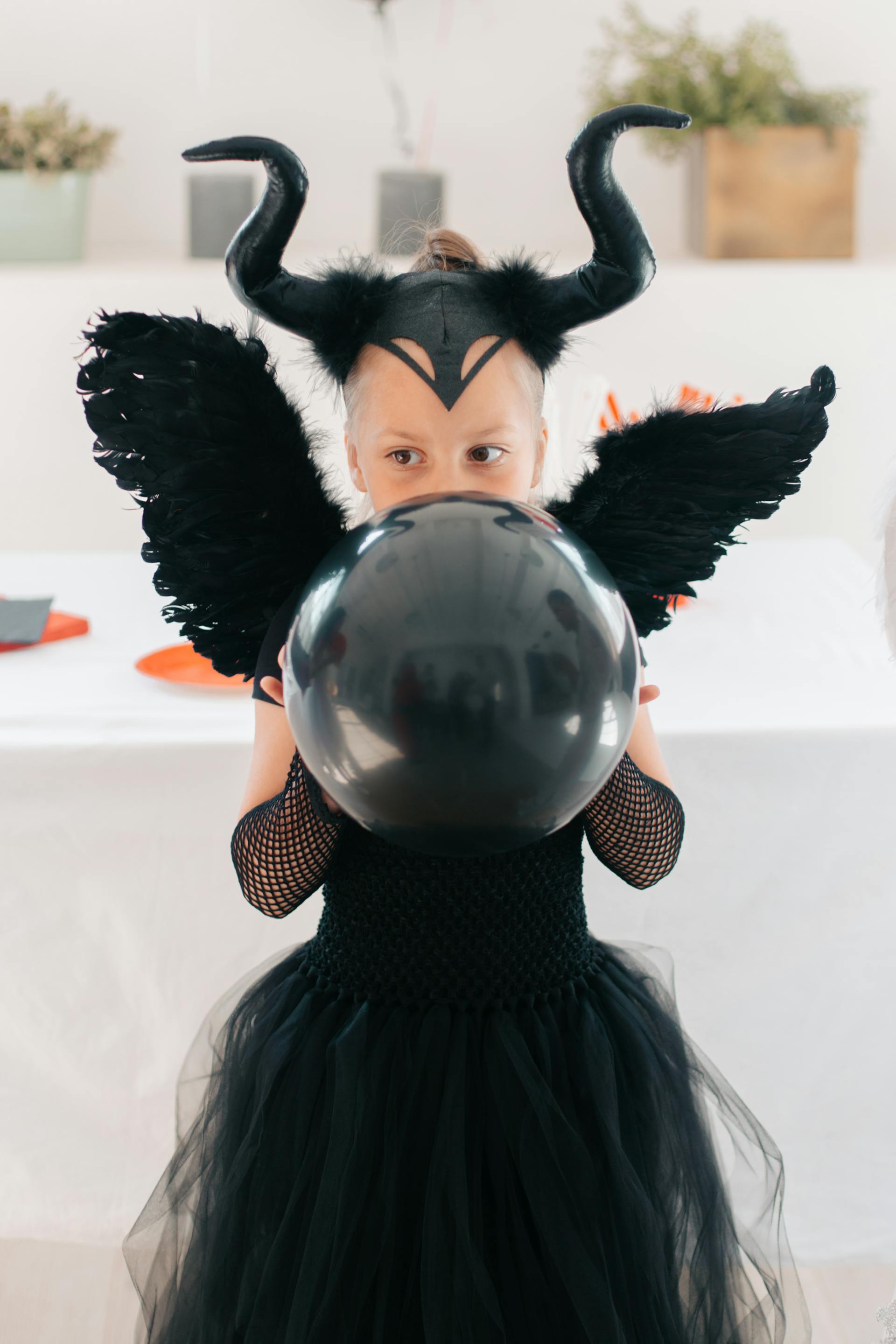 Ein junges Mädchen trägt ein schwarzes Halloween-Kostüm und hält einen Luftballon | Quelle: Pexels