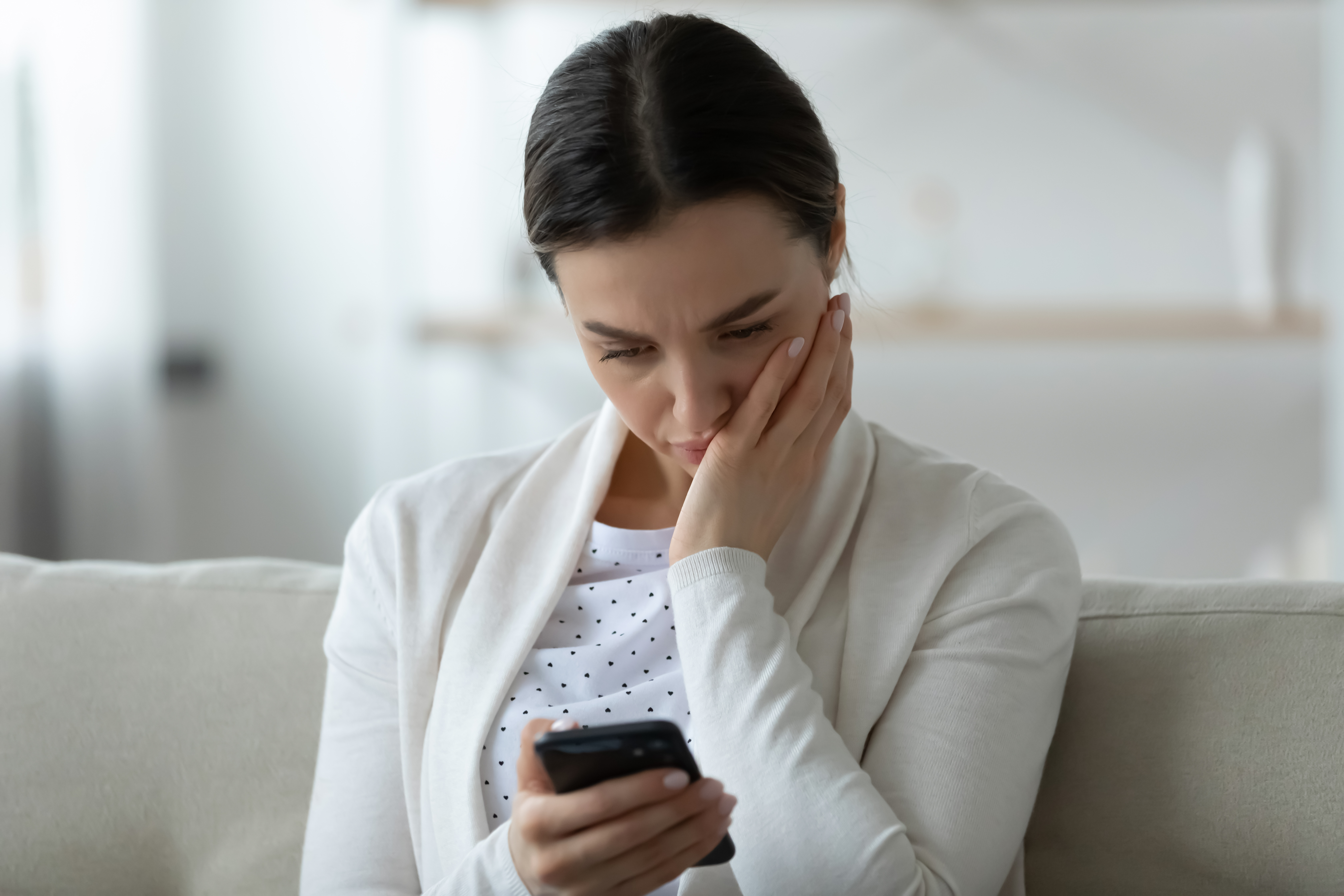 Eine verzweifelte Frau hält ihr Smartphone in der Hand | Quelle: Shutterstock