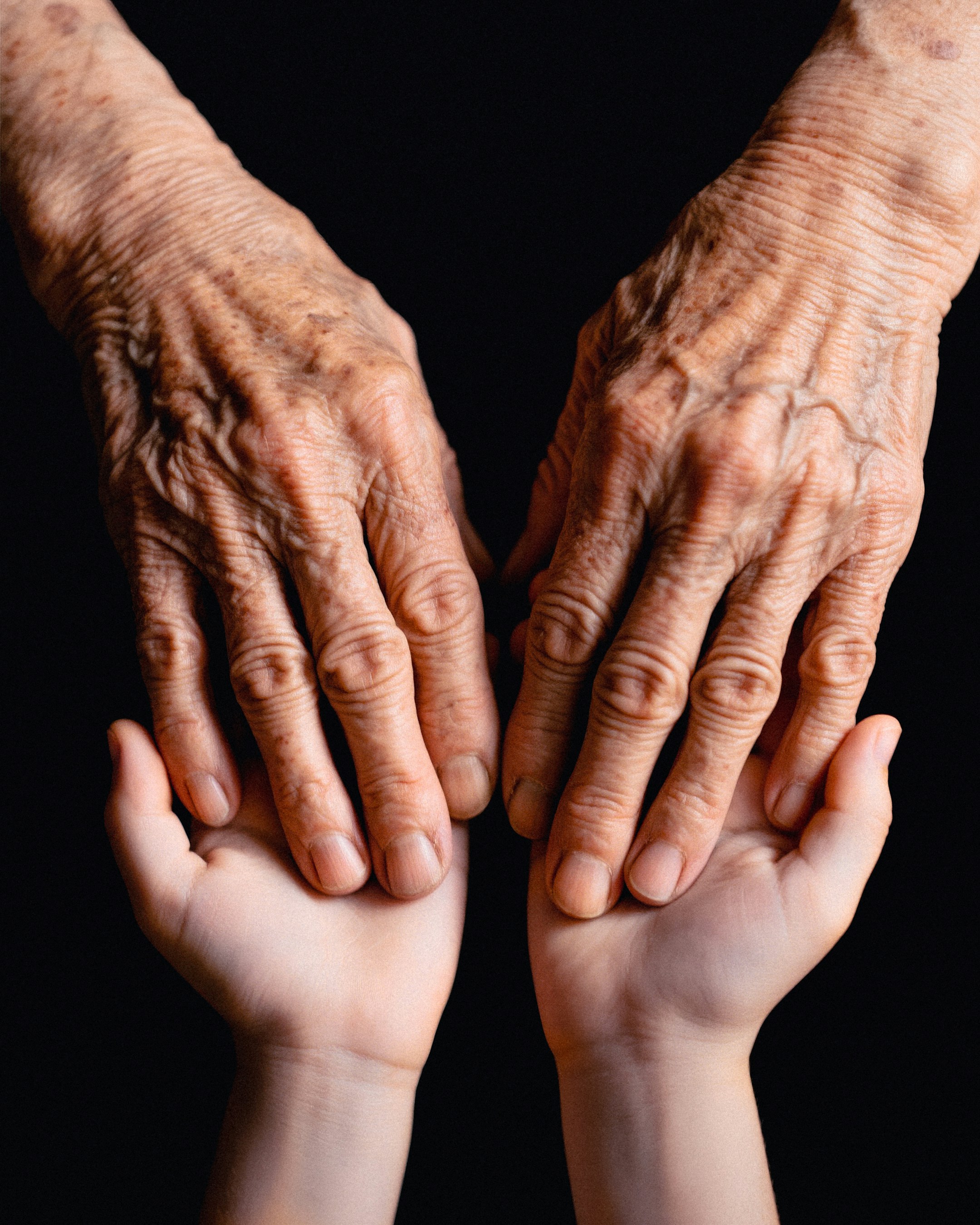 Die Hände eines jungen und eines älteren Menschen berühren sich | Quelle: Unsplash