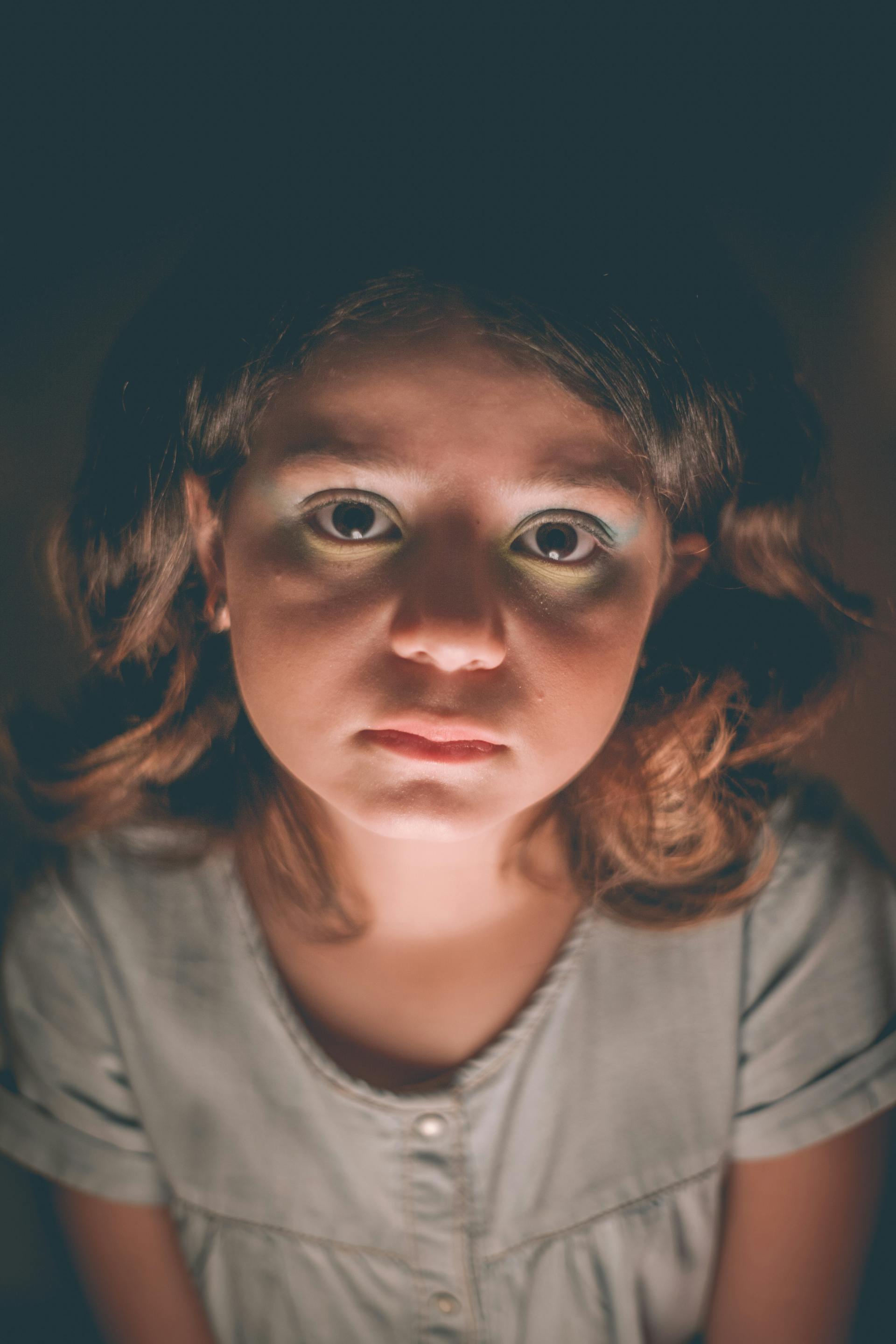 Ein traurig aussehendes Mädchen in einem dunklen Raum | Quelle: Pexels