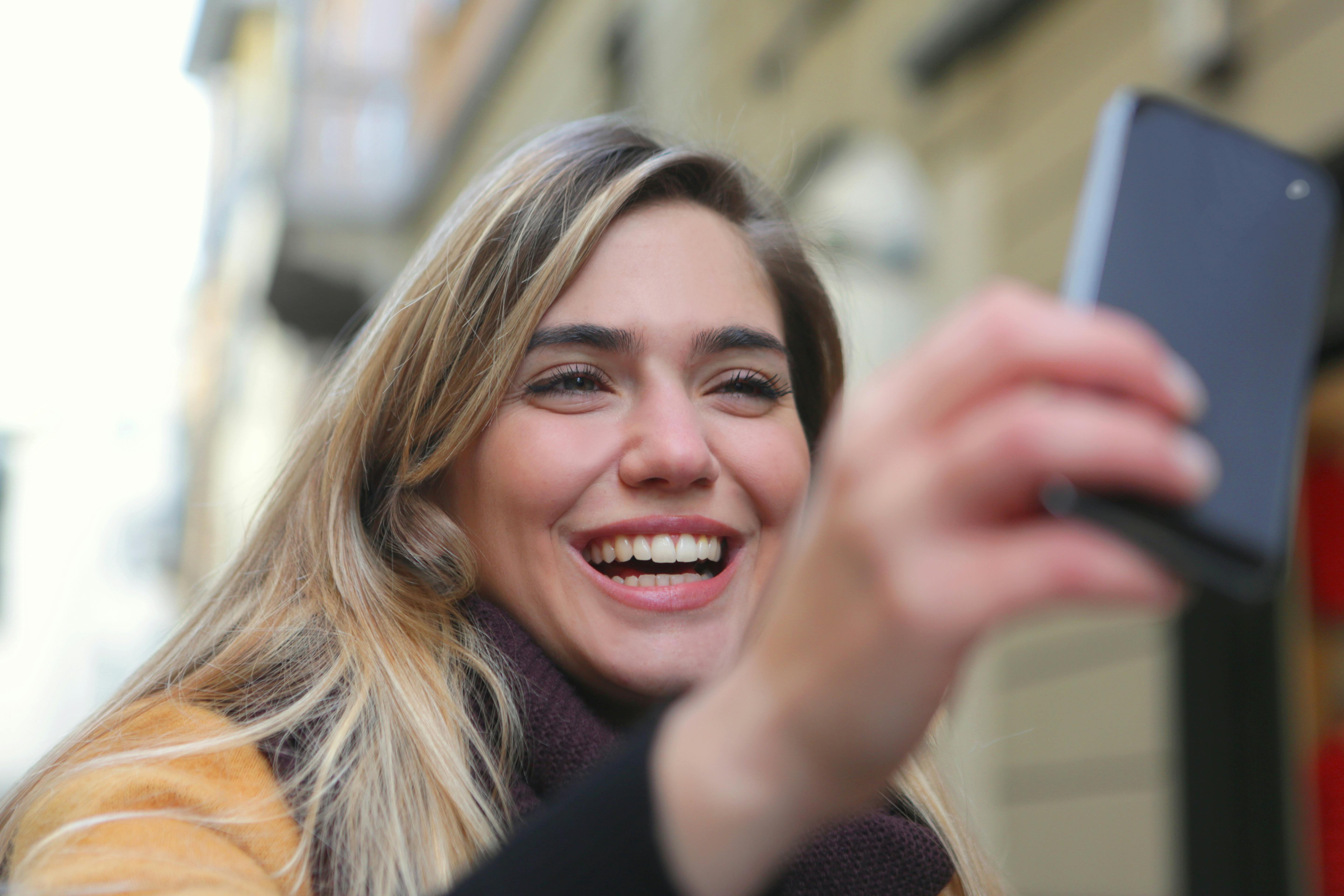 Eine glückliche Frau, die ihr Telefon benutzt | Quelle: Pexels