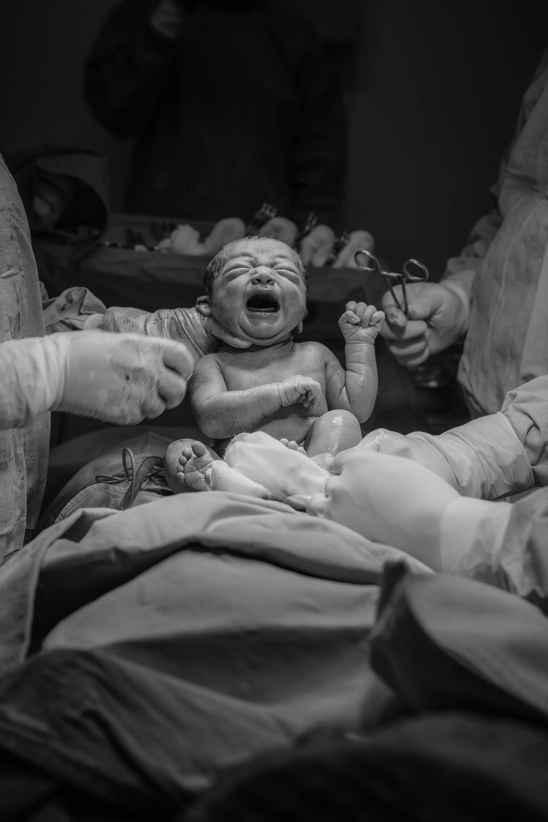 Ein Graustufenfoto von Krankenhauspersonal, das ein neugeborenes Baby hält | Quelle: Pexels