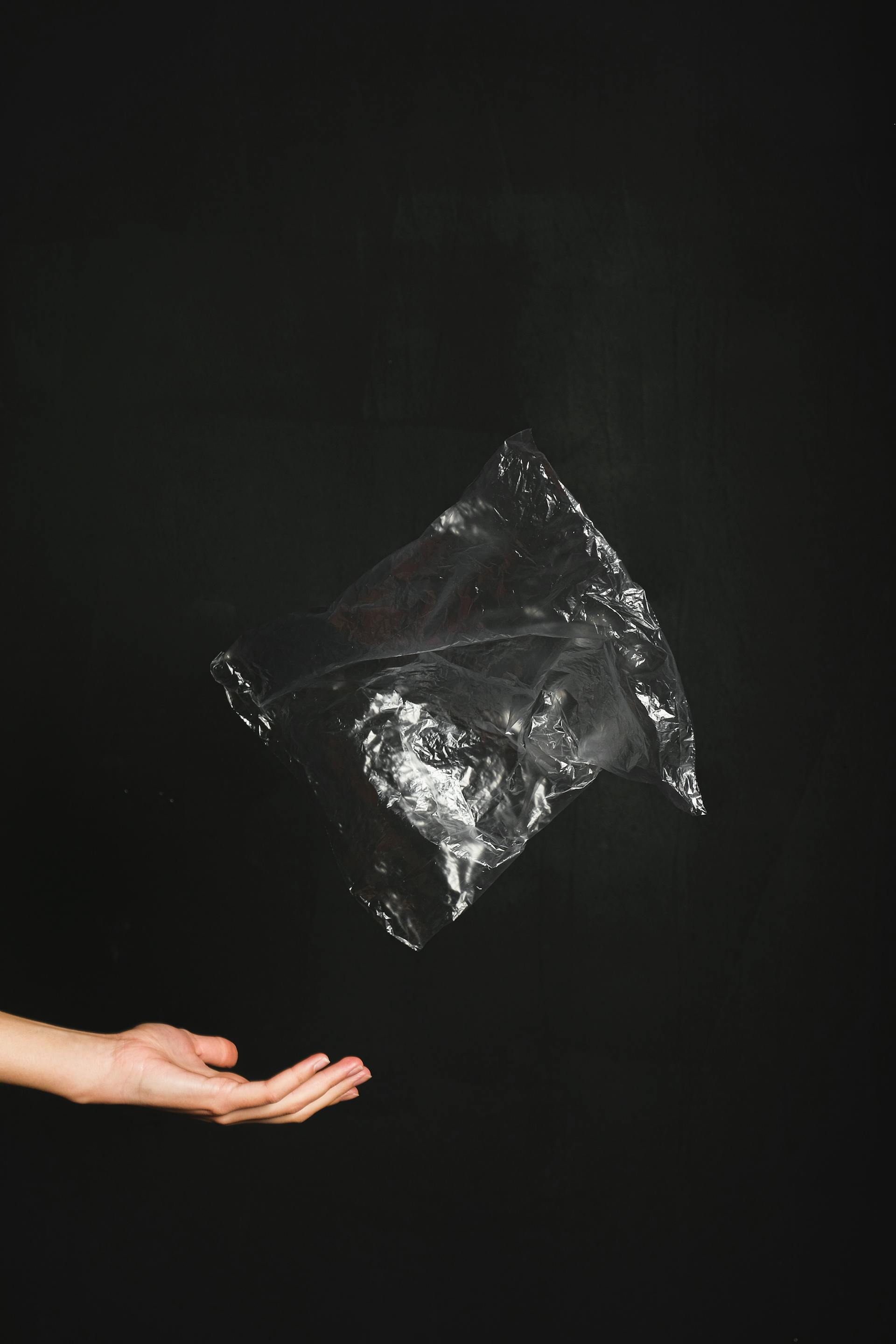 Eine Nahaufnahme einer Hand, die eine schwarze Plastiktüte wirft | Quelle: Pexels