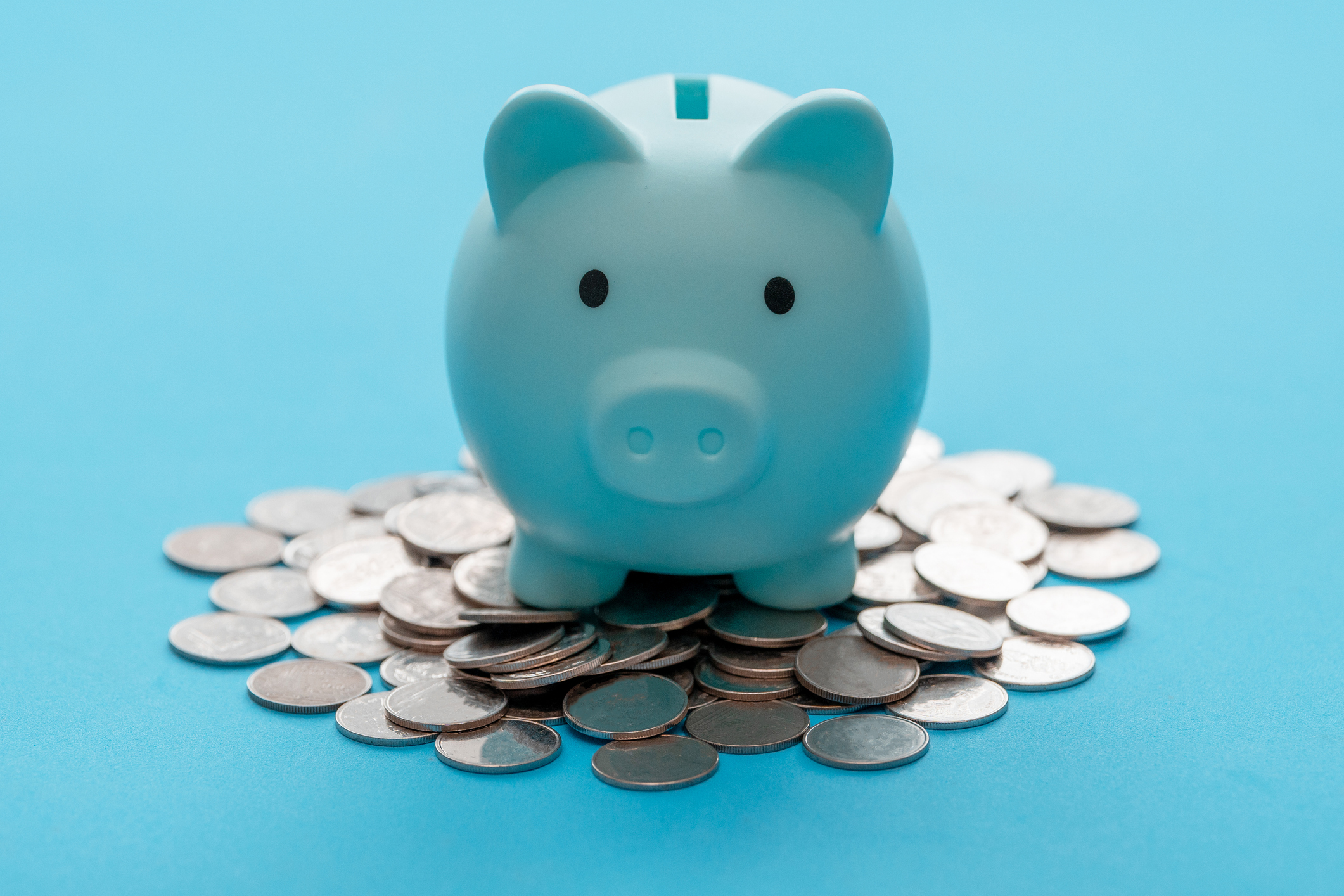 Sparschwein und Münze auf hellblauem Hintergrund zum Geldsparen | Quelle: Getty Images