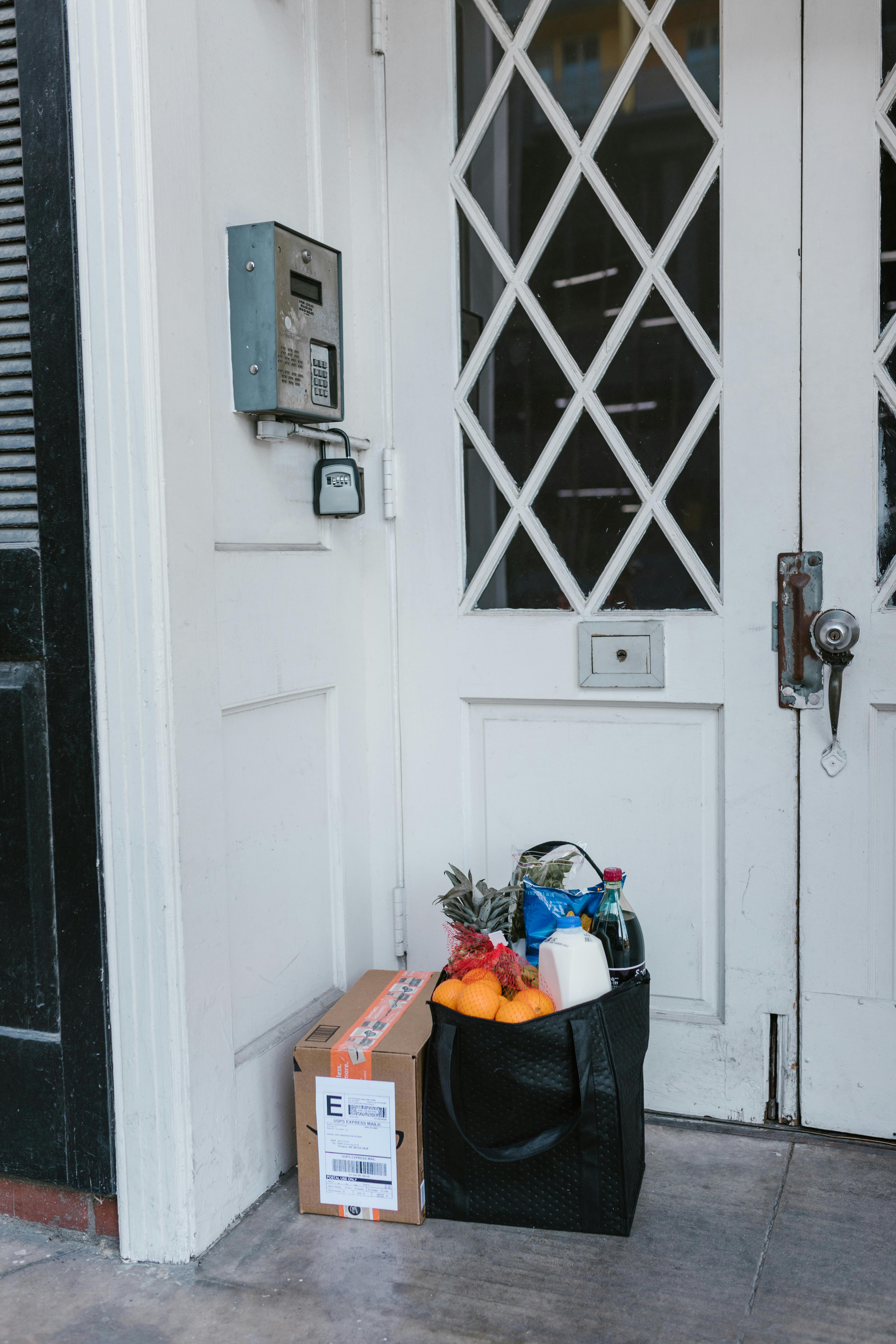 Einkaufstüte und ein Paket vor einer Haustür | Quelle: Pexels