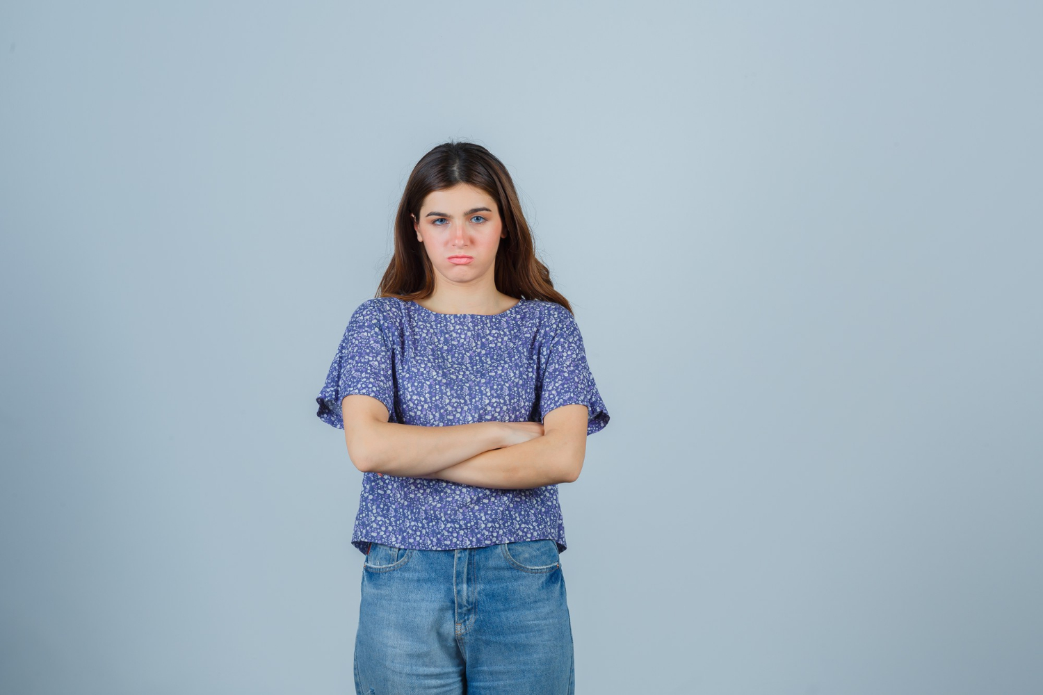Eine frustrierte junge Frau mit verschränkten Armen | Quelle: Freepik
