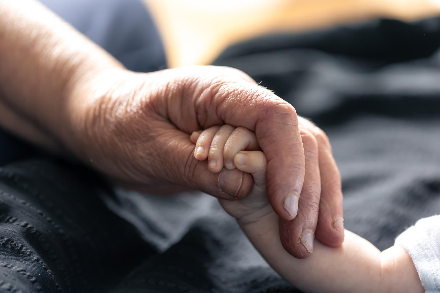Eine ältere Person hält die Hand eines Babys | Quelle: Freepik
