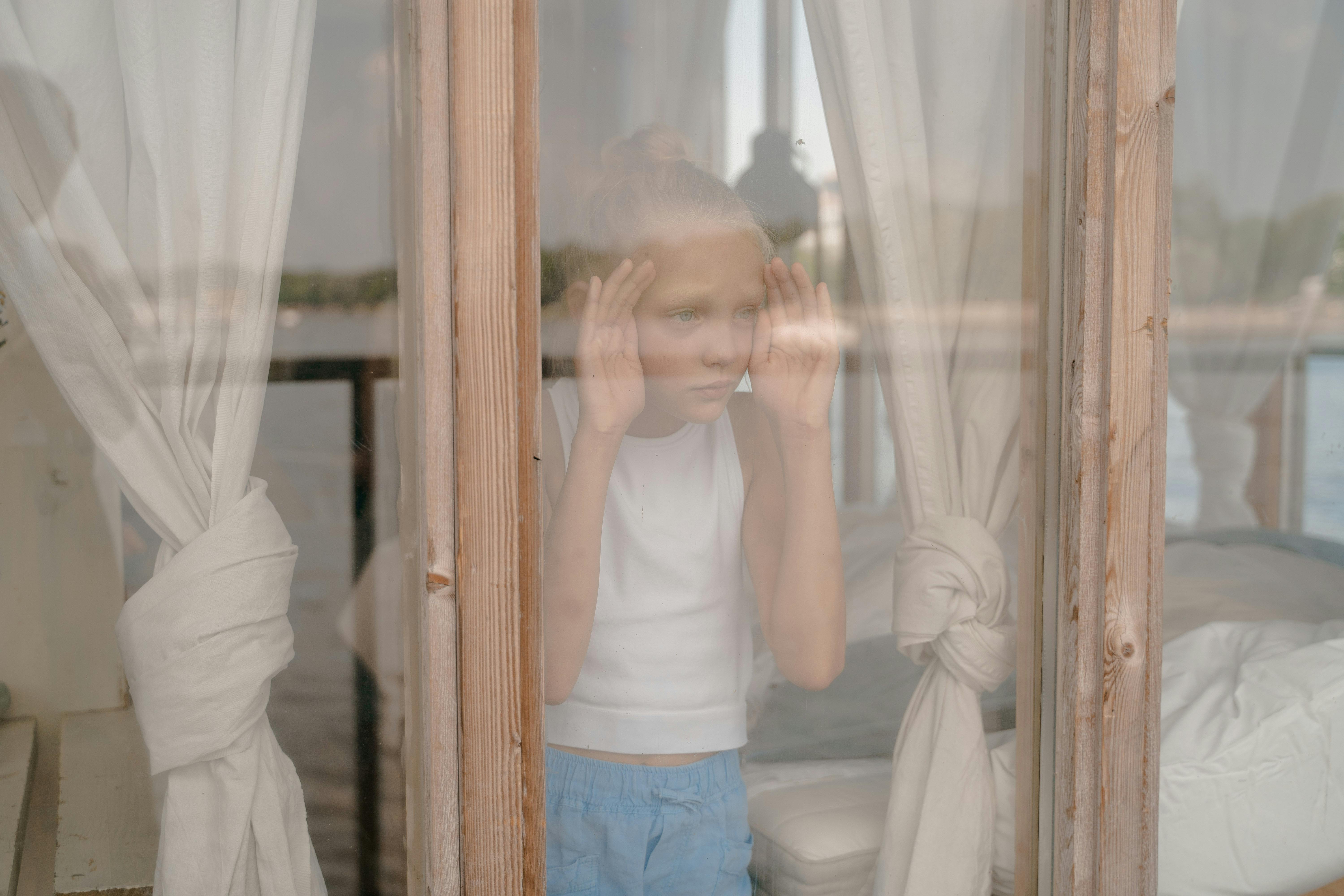 Ein Kind schaut durch ein Fenster | Quelle: Pexels