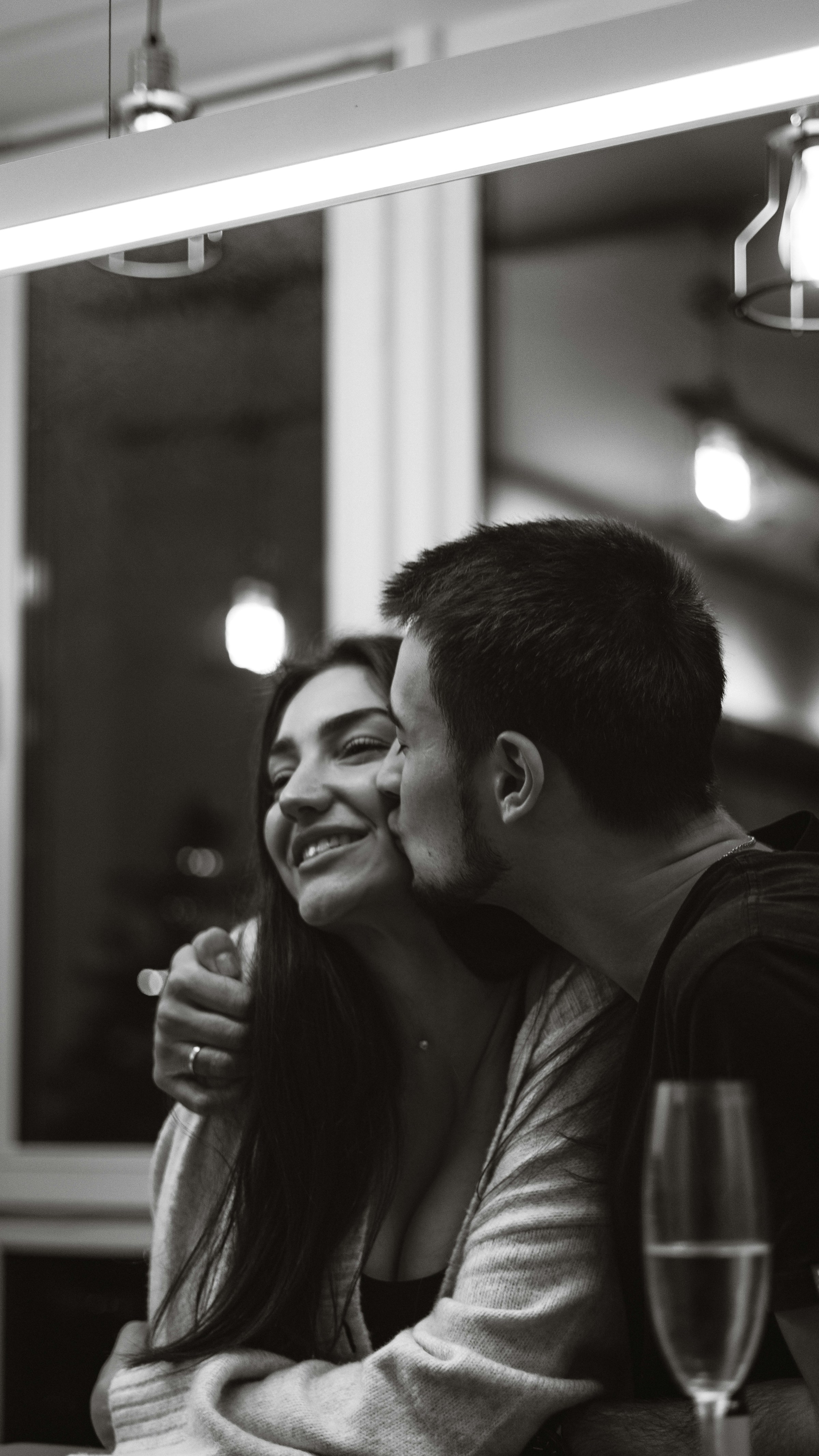 Ein Graustufenfoto von einem Mann, der eine Frau auf die Wange küsst | Quelle: Unsplash