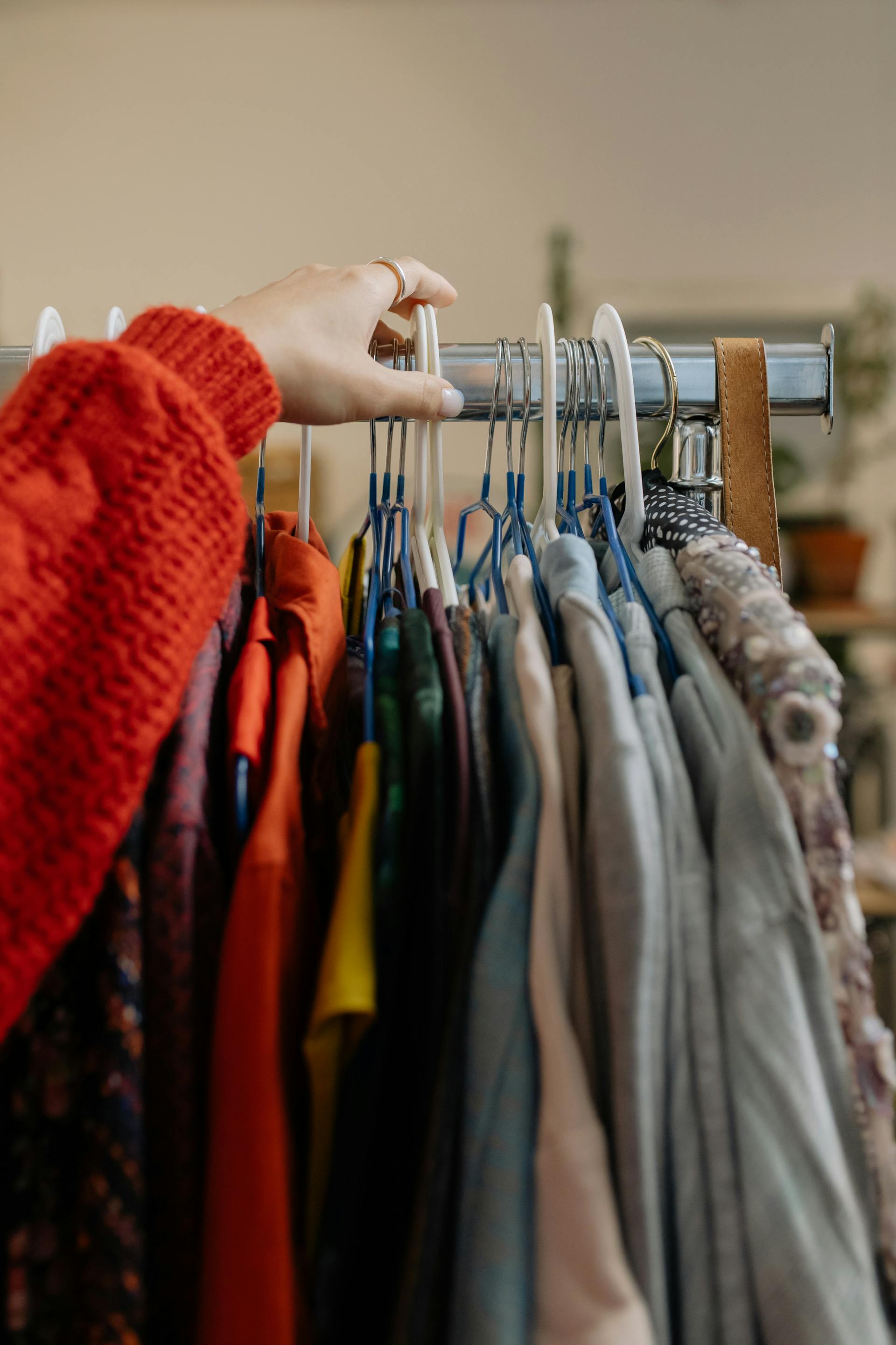Eine Nahaufnahme einer Person, die die in einem Laden hängende Kleidung berührt | Quelle: Pexels