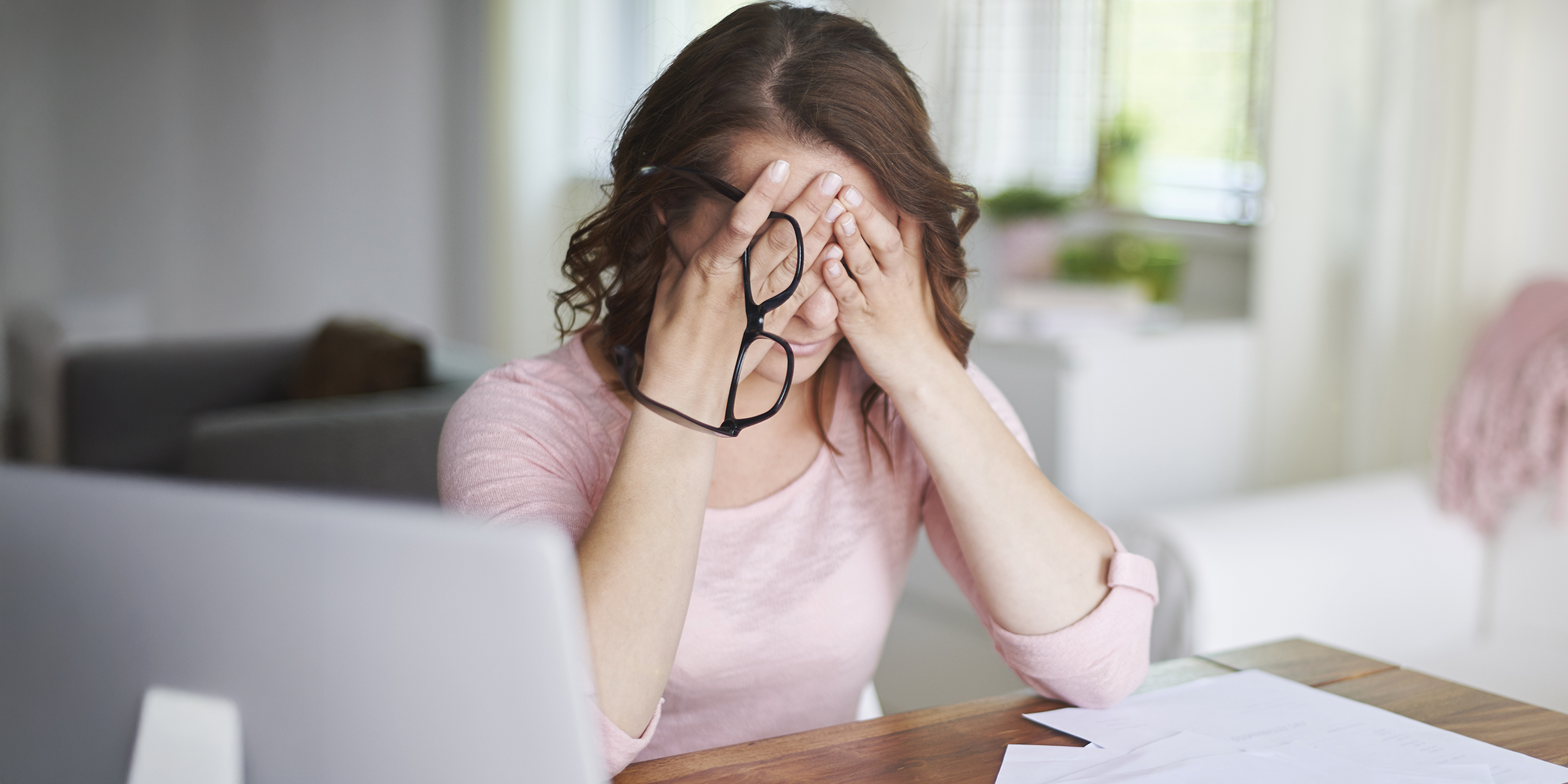 Eine besorgte Frau sitzt mit dem Kopf in den Händen | Quelle: Shutterstock