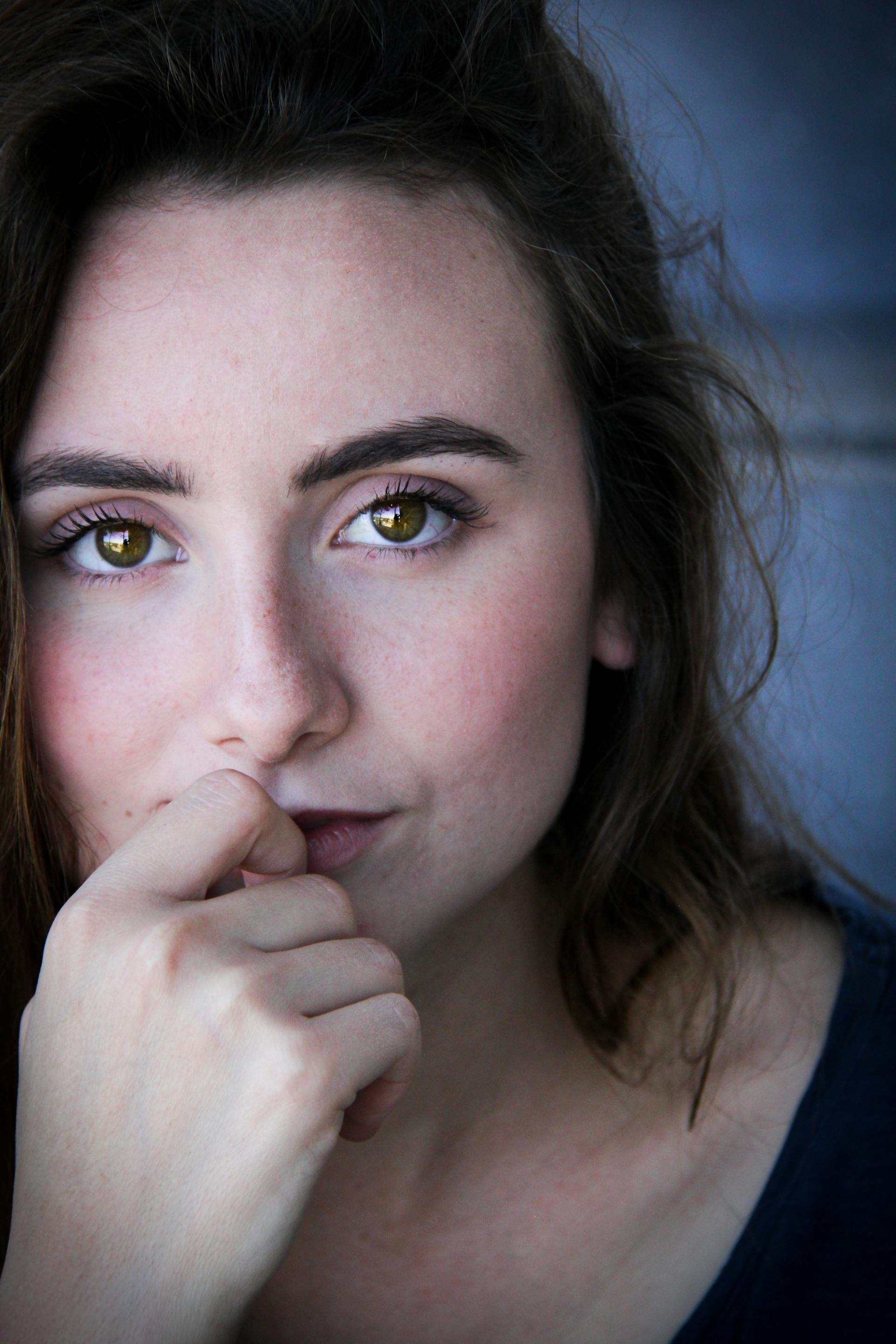 Eine braunhaarige Frau mit grünen Augen hält ihren Finger an die Lippen | Quelle: Pexels