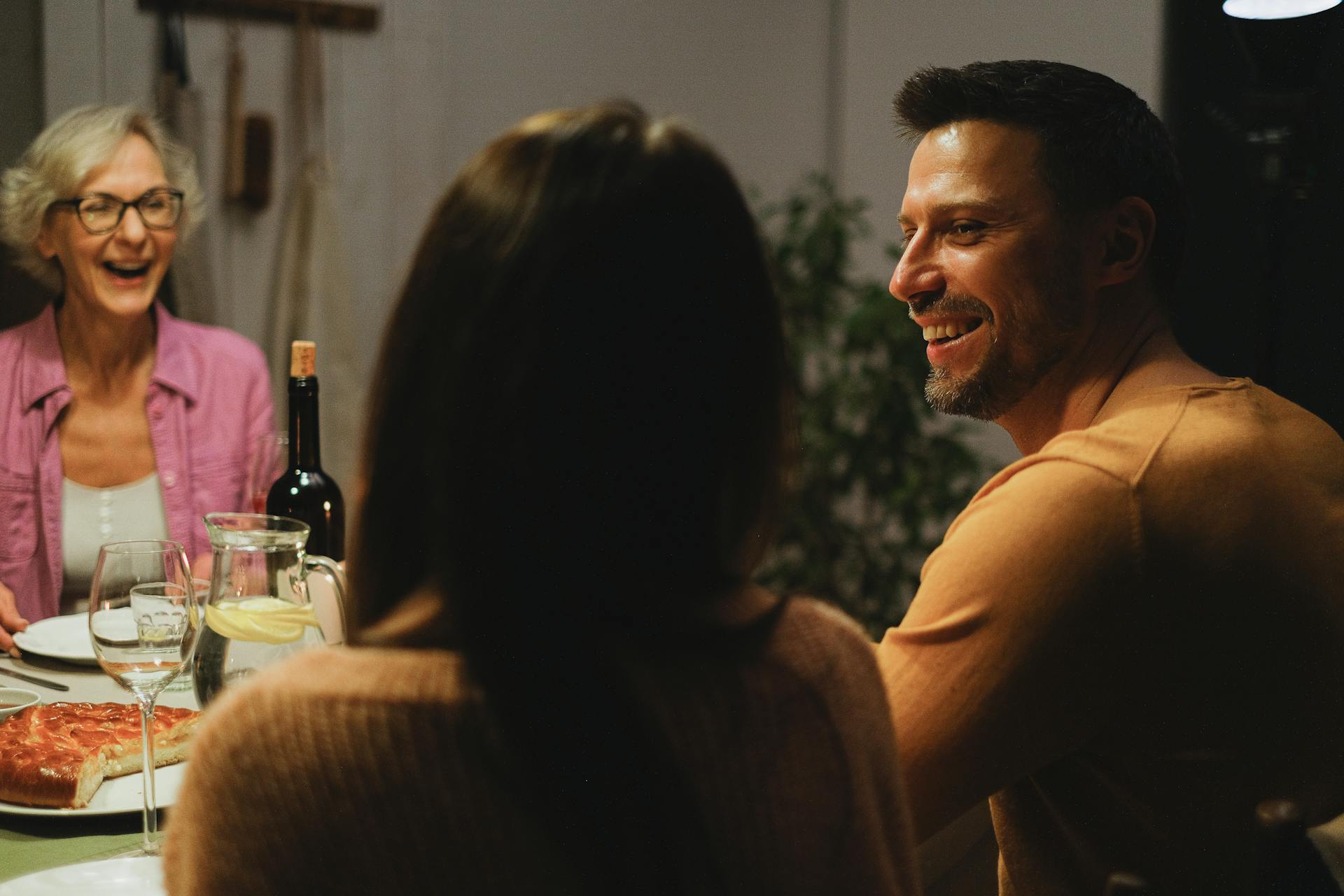 Ein Mann lacht bei einem Familienessen | Quelle: Pexels