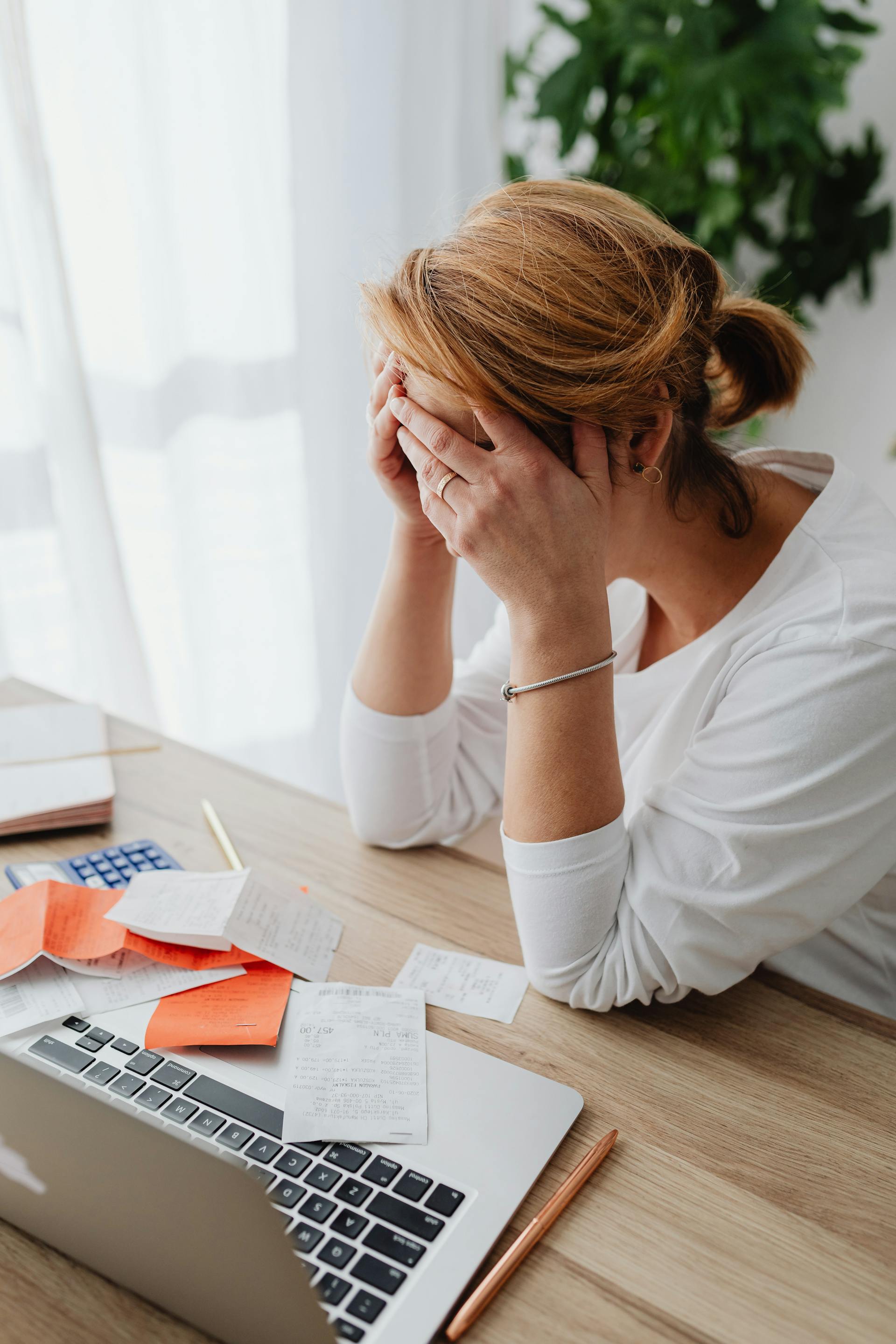 Eine verzweifelte Frau sitzt an einem Schreibtisch | Quelle: Pexels