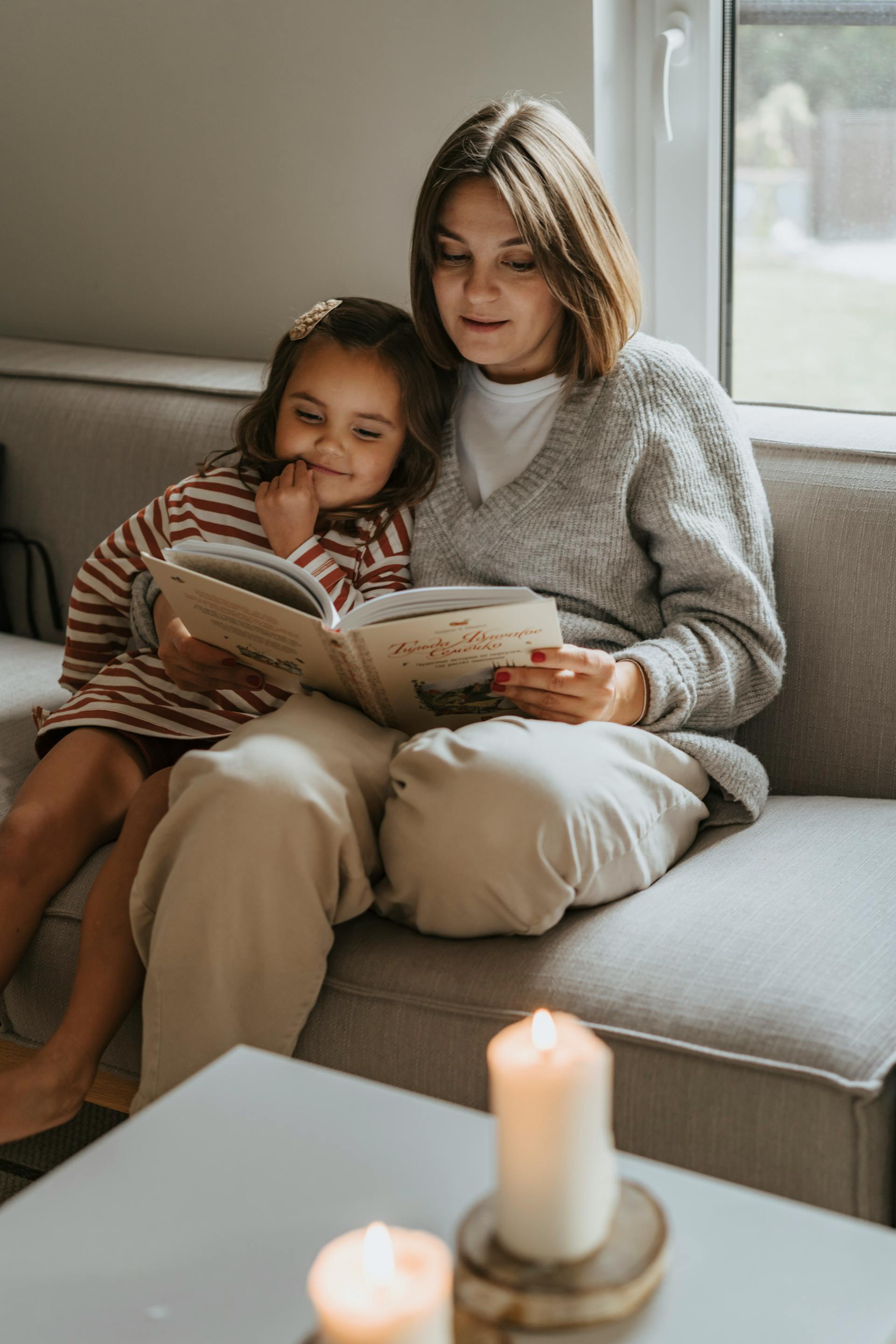 Eine Frau liest einem kleinen Mädchen auf einer Couch vor | Quelle: Pexels
