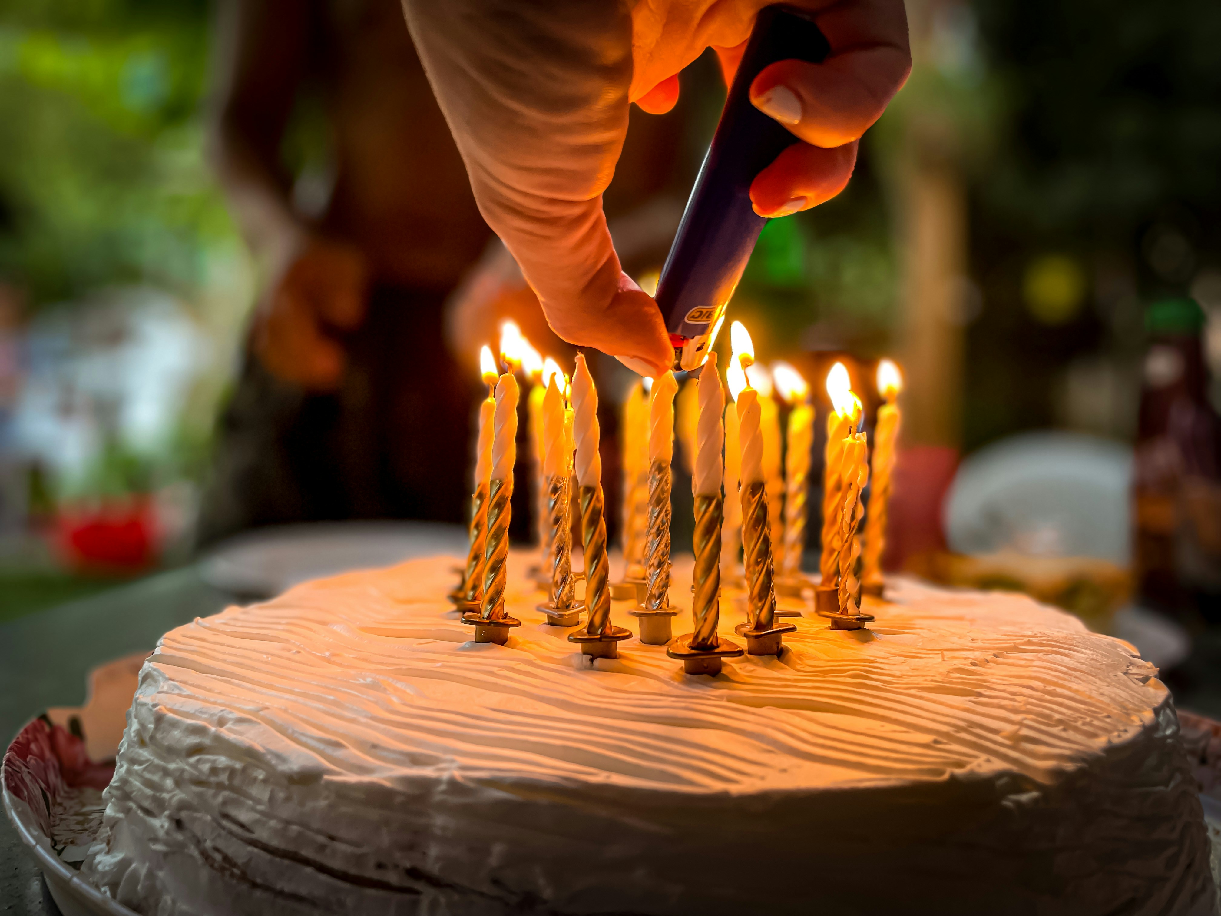 Die Hand einer Frau zündet die Kerzen auf einer Torte an | Quelle: Unsplash