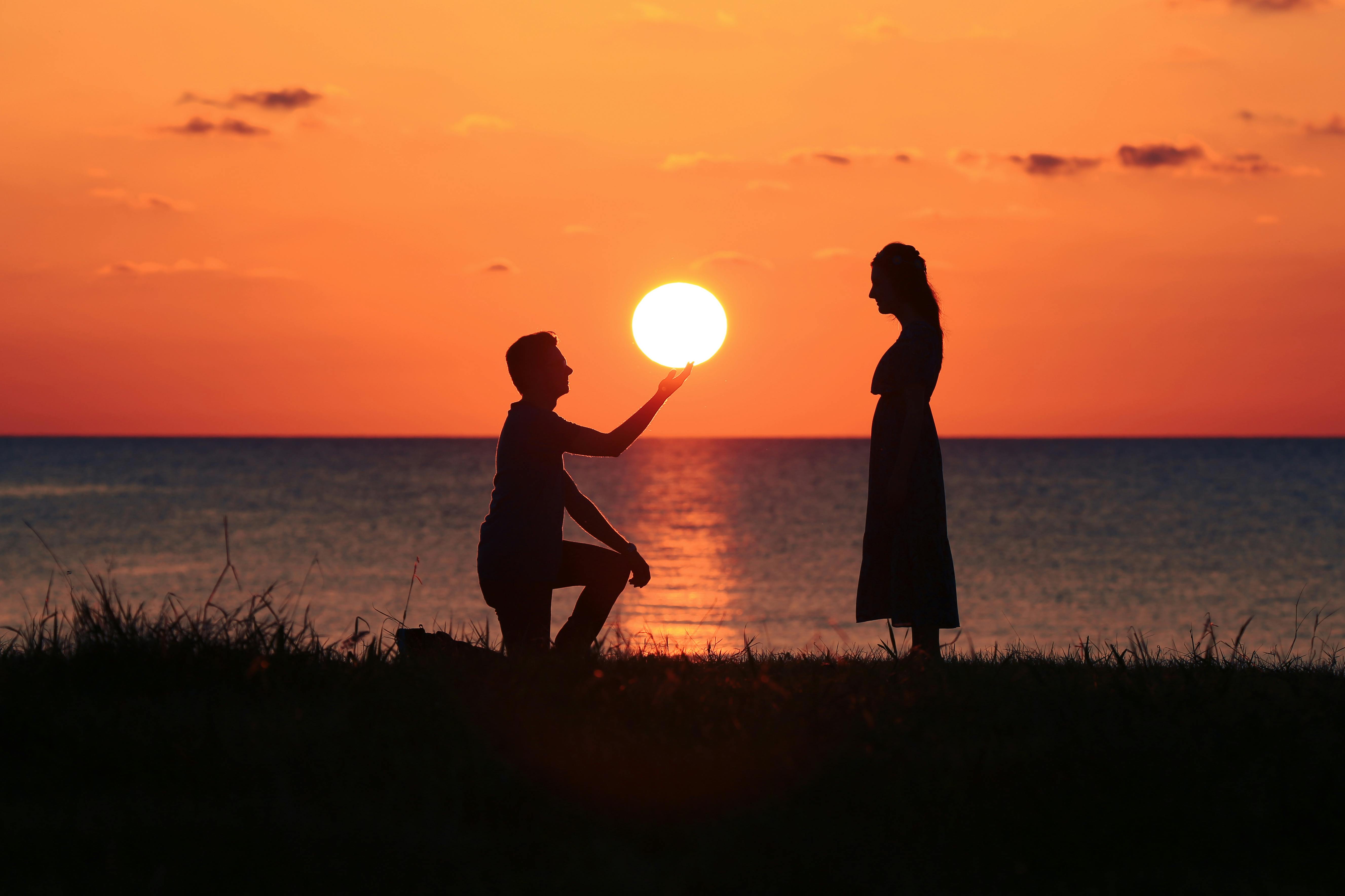 Silhouette eines Mannes, der bei Sonnenuntergang vor einer Frau kniet | Quelle: Pexels