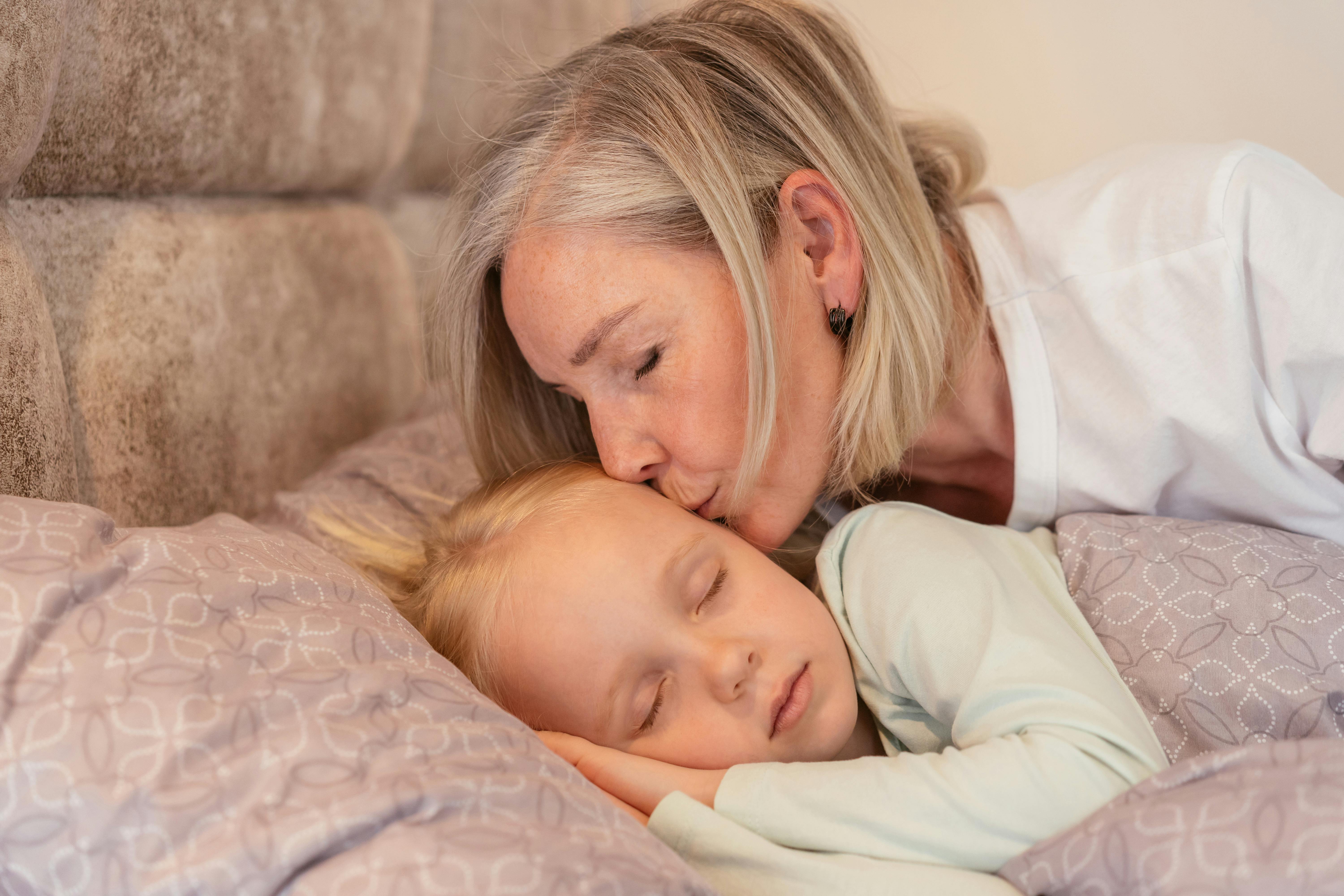 Eine Großmutter, die ihre Enkelin ins Bett bringt | Quelle: Pexels