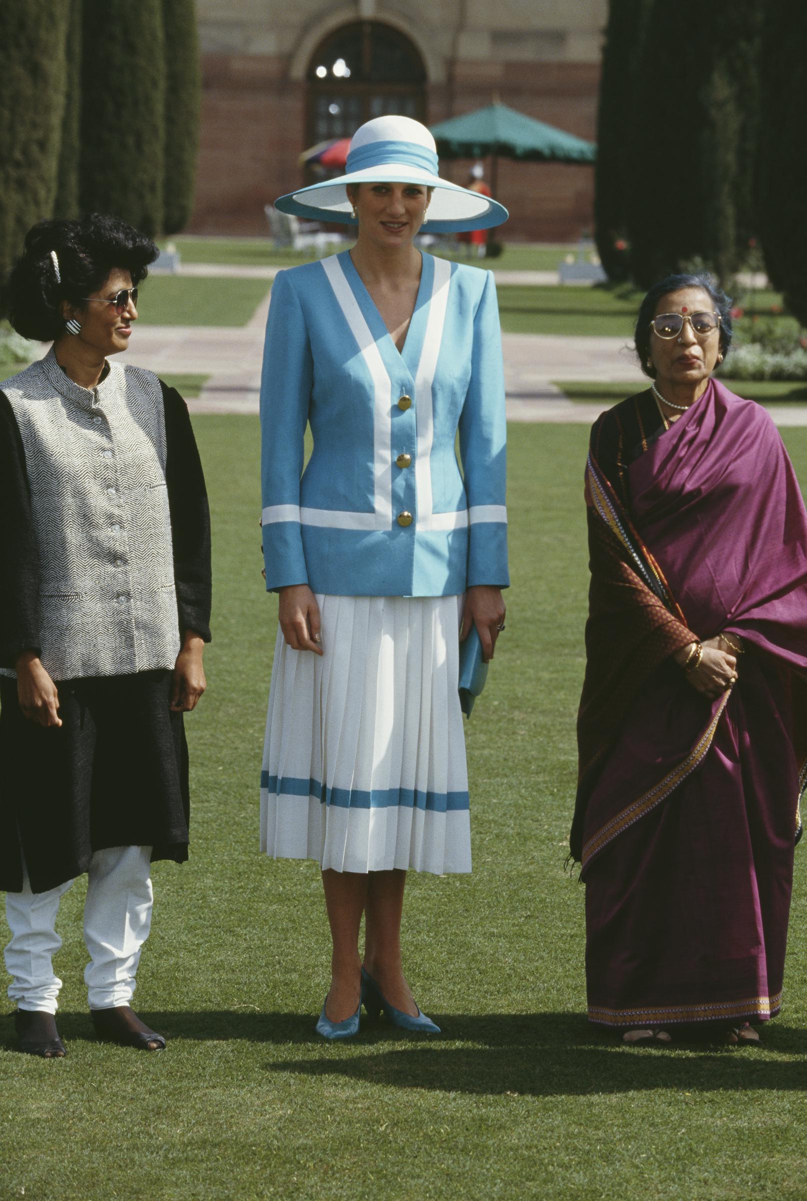 Prinzessin Diana steht neben Janaki Venkataraman, der Frau des indischen Präsidenten, im Rashtrapati Bhavan am 12. Februar 1992. In ihrem blau-weißen Ensemble strahlt Diana diplomatische Eleganz aus, während die beiden Frauen einen ruhigen Moment vor der Kulisse des großen indischen Präsidentenpalastes verbringen.