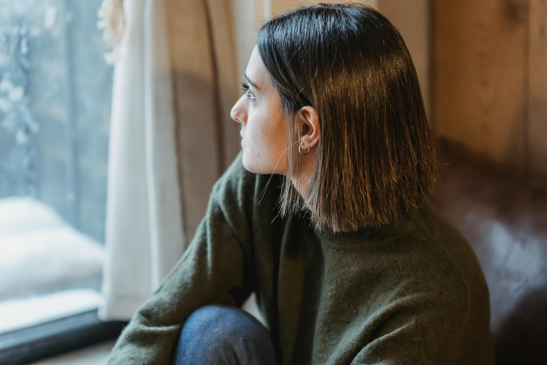 Eine nachdenkliche Frau, die am Fenster sitzt | Quelle: Pexels