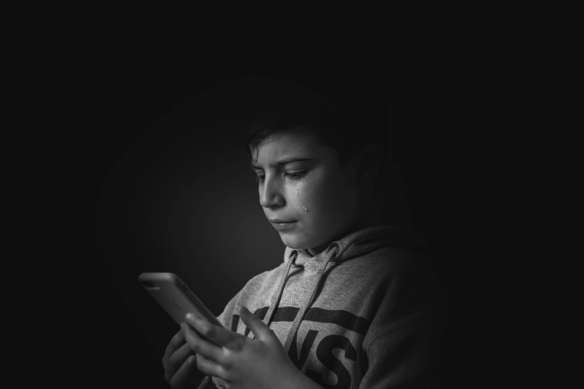 Ein Junge mit Tränen in den Augen, der auf sein Handy schaut | Quelle: Pexels