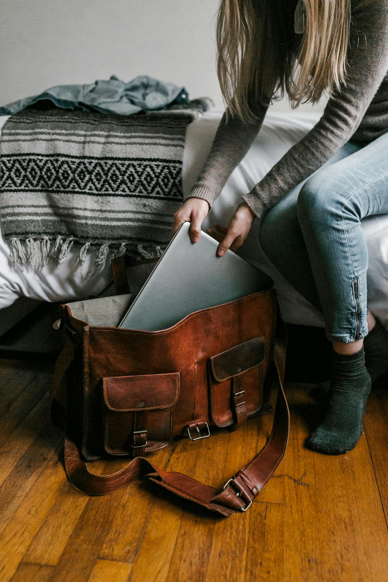 Eine Frau packt einen Laptop in eine braune Tasche | Quelle: Pexels