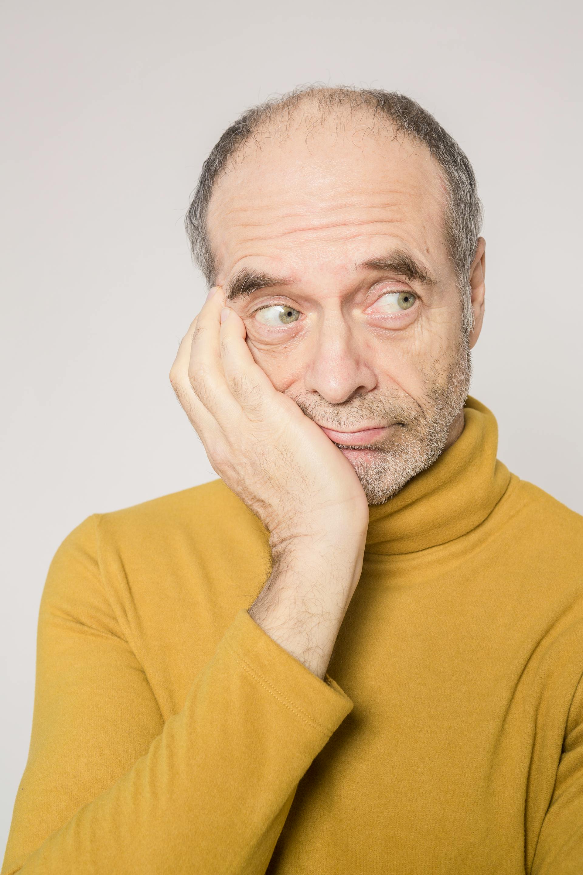 Ein älterer Mann in einem gelben Pullover schaut zur Seite | Quelle: Pexels