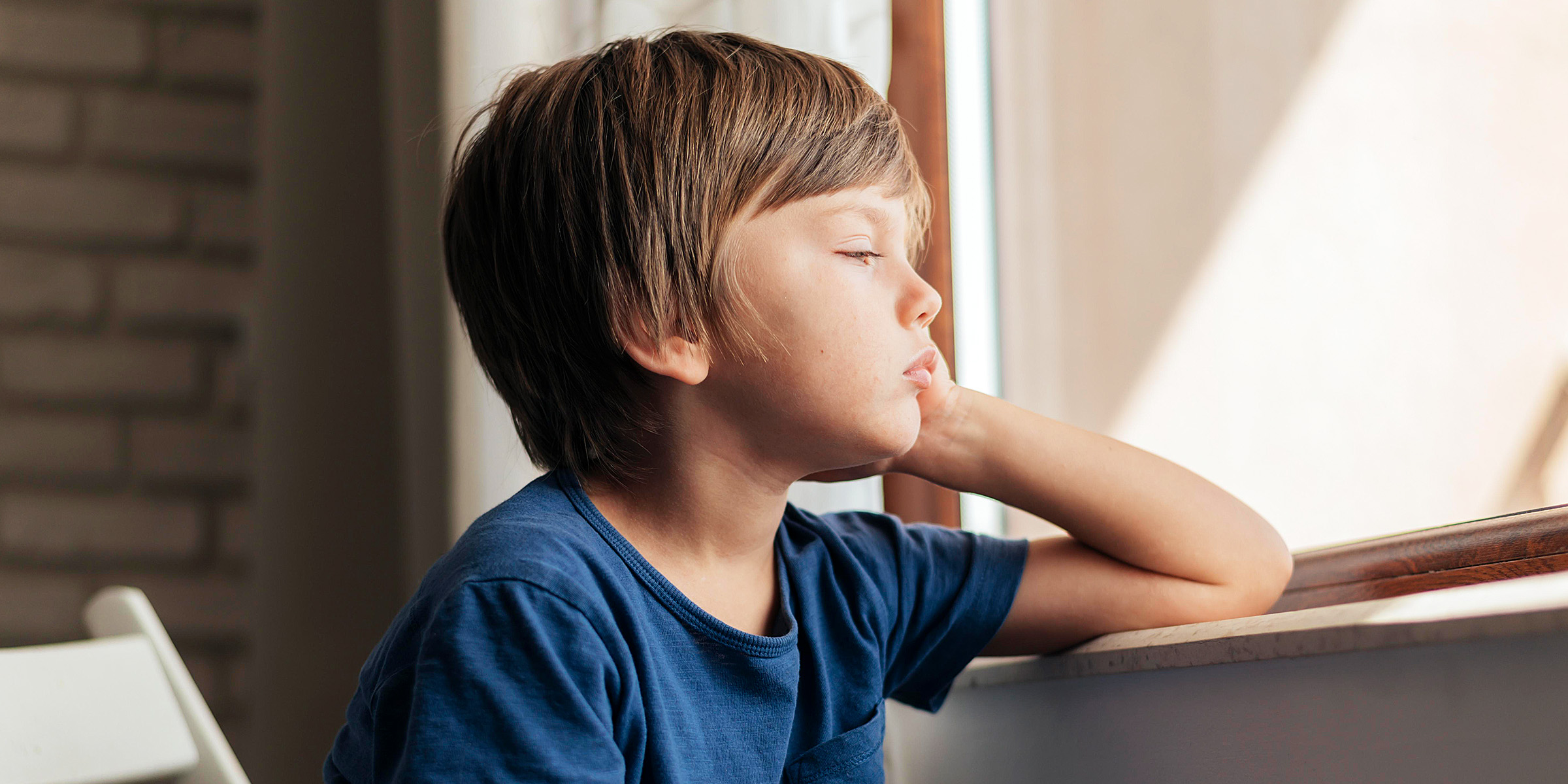 Ein trauriger kleiner Junge sitzt am Fenster | Quelle: Freepik