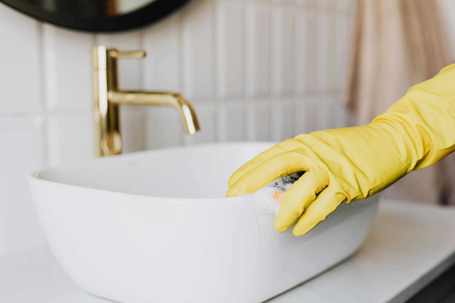 Eine Person, die ein Waschbecken im Badezimmer reinigt | Quelle: Pexels