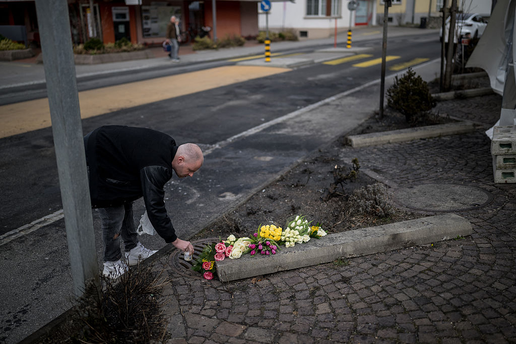 Ein Mann legt am 11. März 2026 in Kerzers in der Westschweiz Blumen nieder; dort war am 10. März 2026 ein Bus in Brand geraten | Quelle: Getty Images