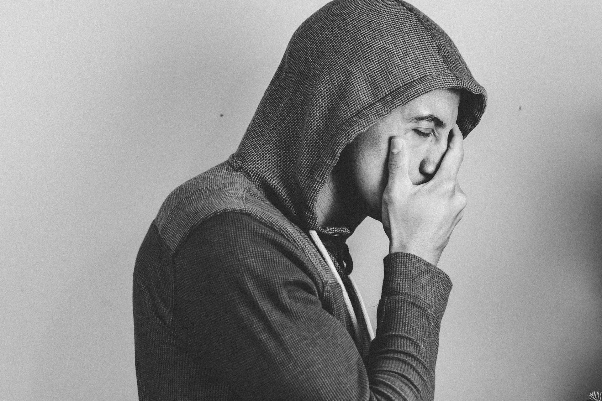 Ein Mann im Kapuzenpulli, der sich das Gesicht hält | Quelle: Pexels