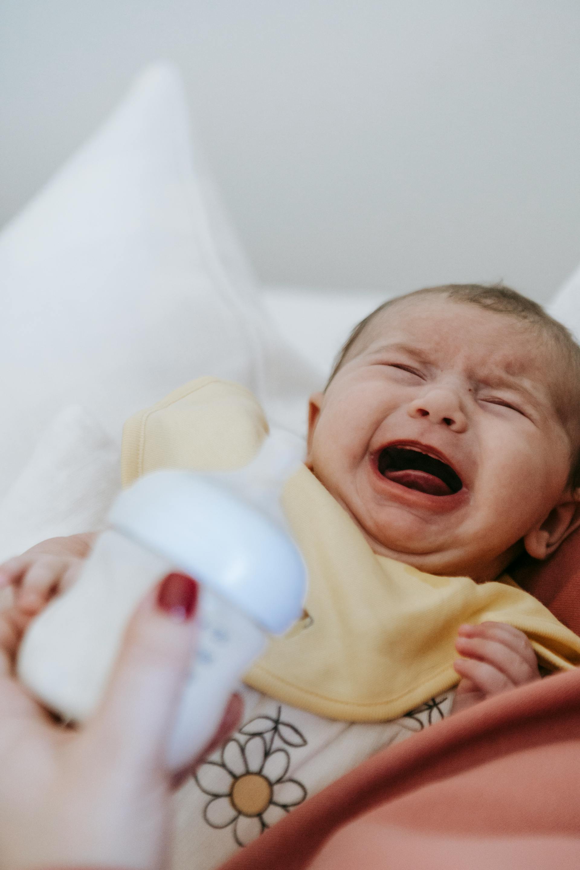 Eine Frau mit einem weinenden Baby und einer Saugflasche in der Hand | Quelle: Pexels